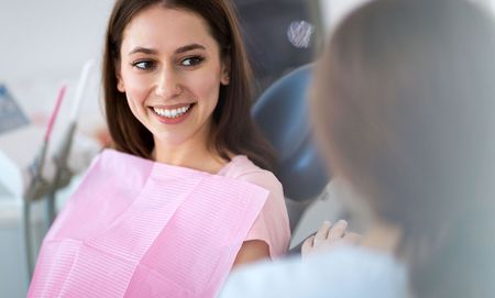 A woman is smiling while sitting in a dental chair.