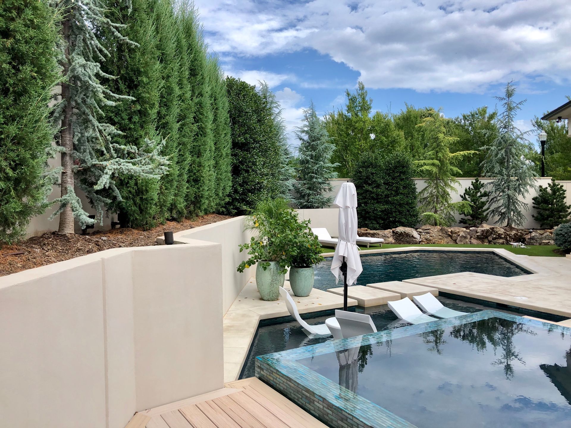 Pool area with a turquoise pool, patio, and stone buildings under a blue sky.