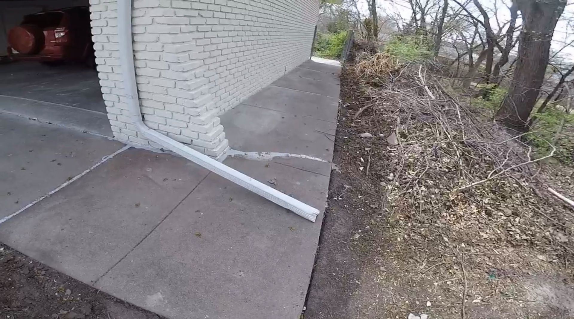 A white brick building with a drain pipe coming out of it.