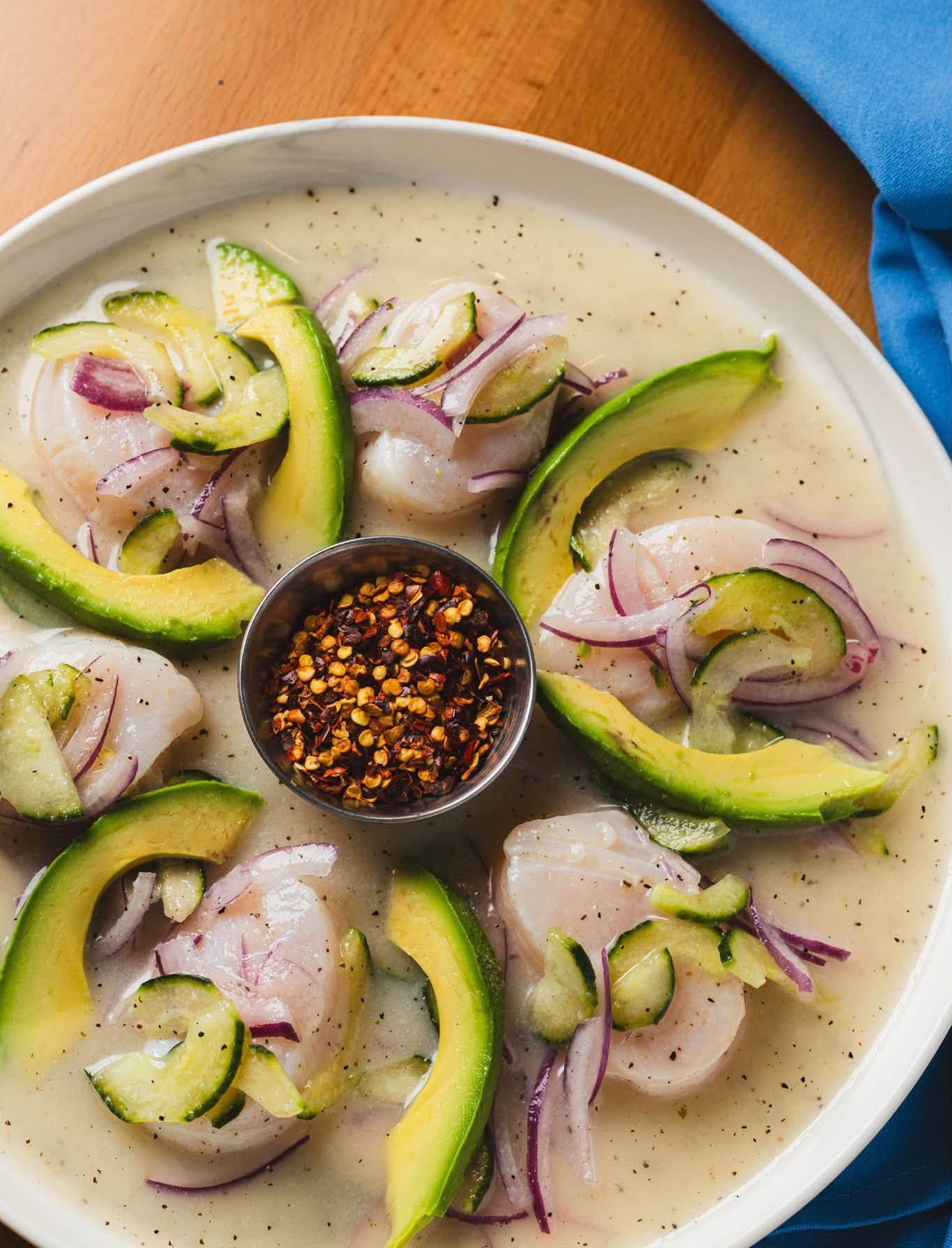 Creamy ceviche with cucumber, red onion, and chili sauce in a white bowl