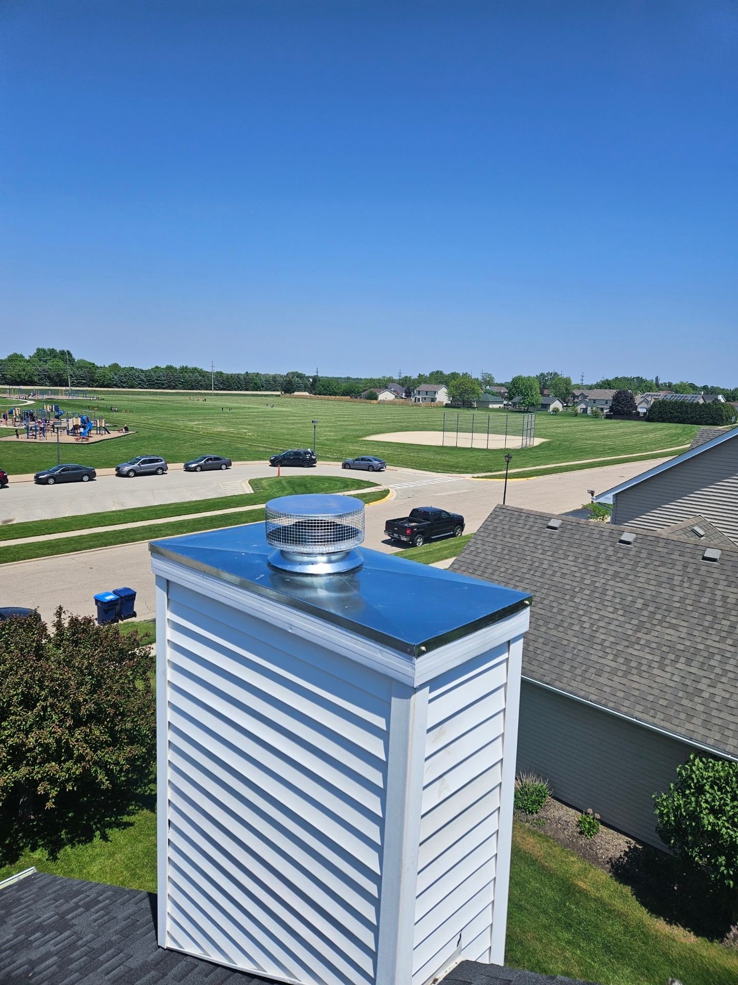 A chimney is sitting on top of a roof with a view of a field.