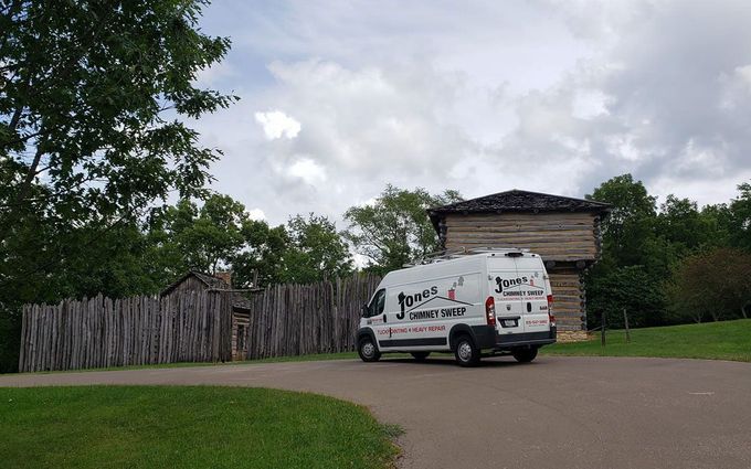 A white van is parked in front of a wooden building.