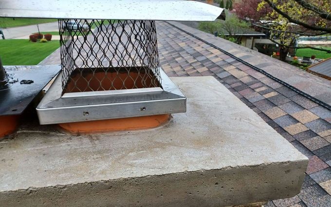 A chimney sitting on top of a concrete platform on a roof.