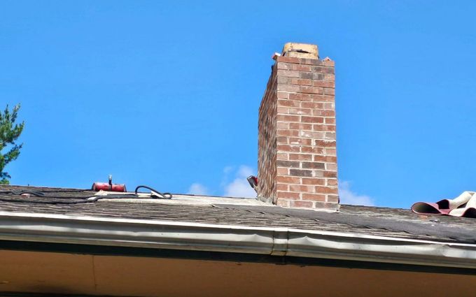 A brick chimney is sitting on top of a roof.