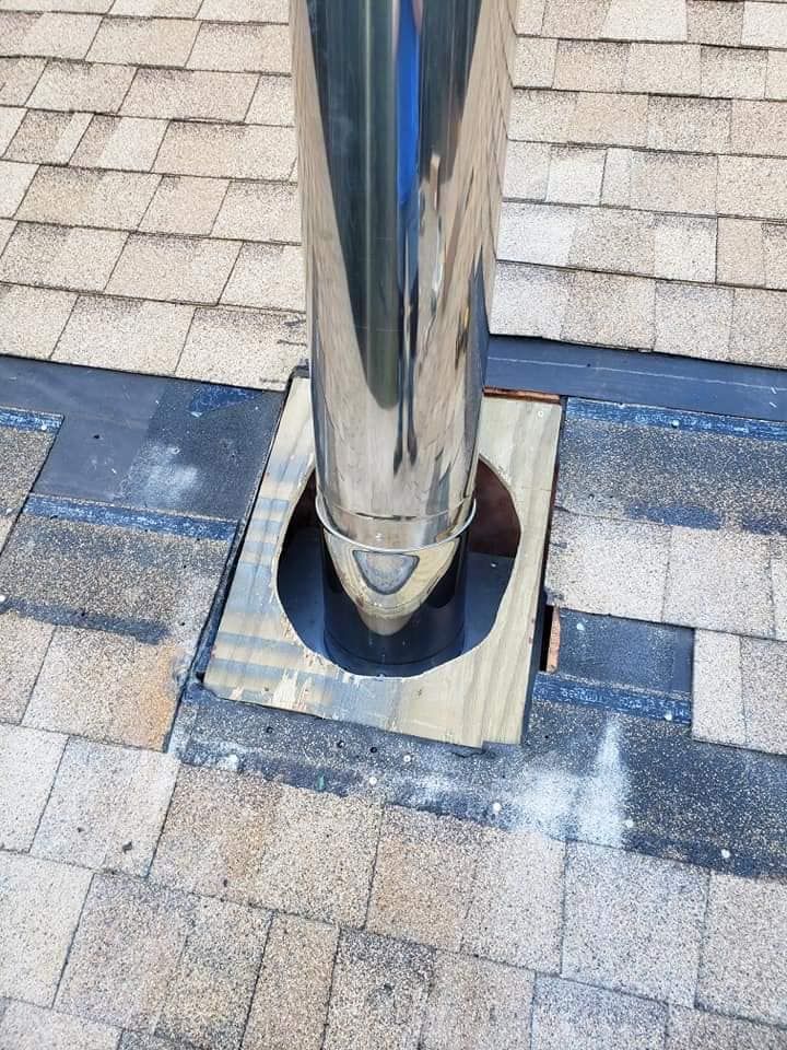 A stainless steel chimney is sitting on top of a brick roof.