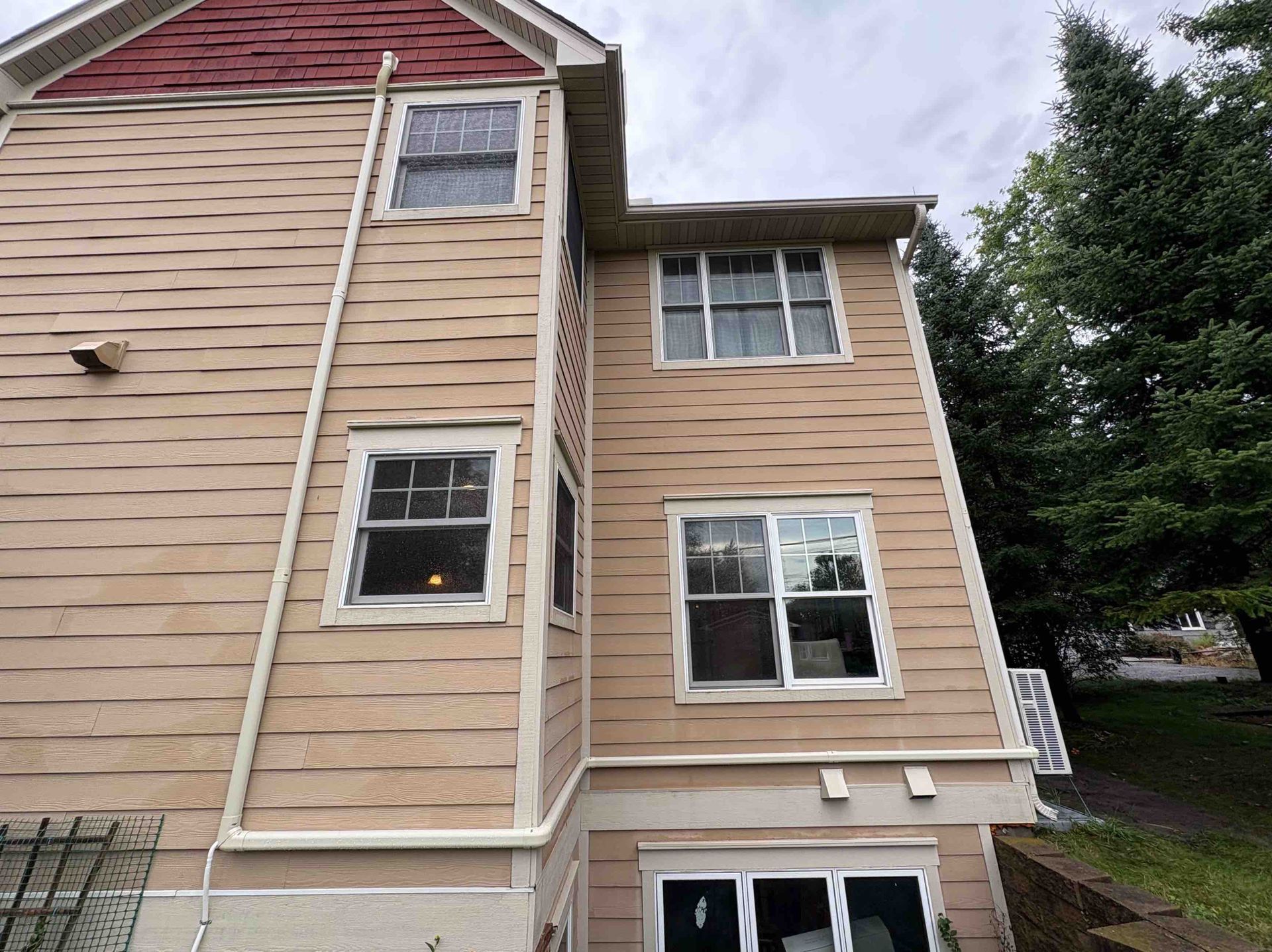 Tan house exterior with multiple windows and red roof.