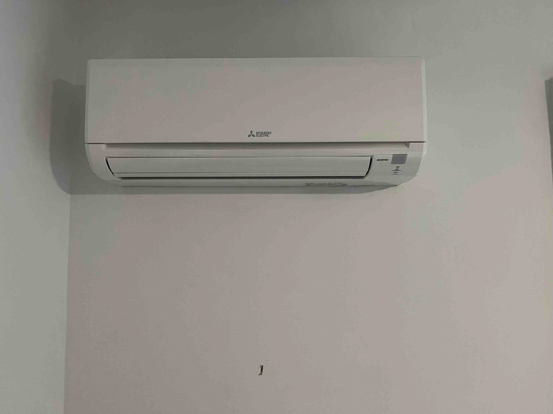 White Mitsubishi air conditioner mounted on a white wall.