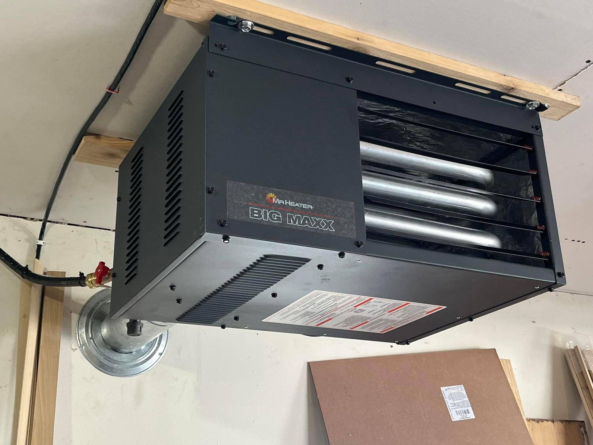 Black overhead garage heater mounted on wooden supports.