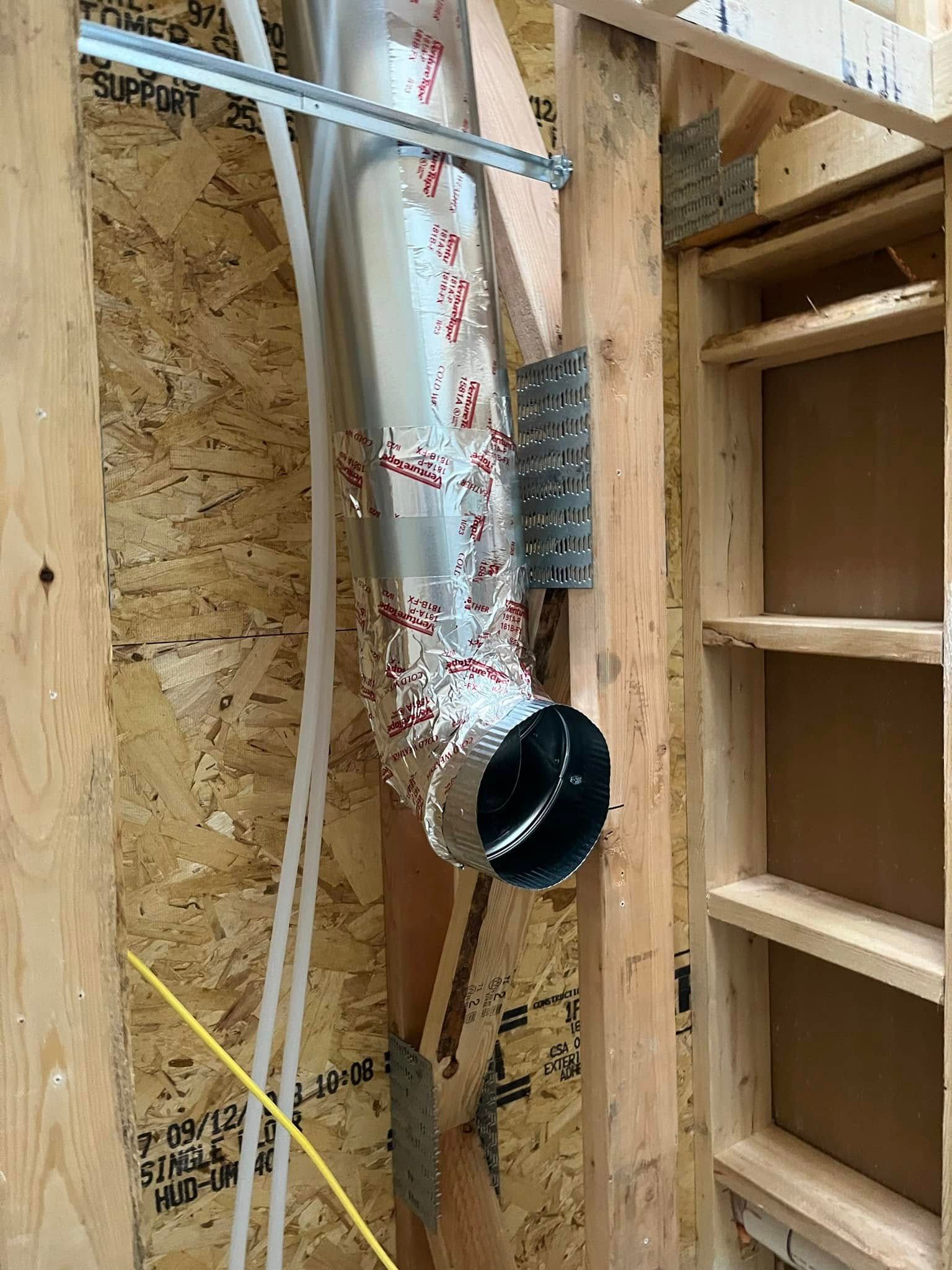 Metal ductwork installed between wood studs in a wall.