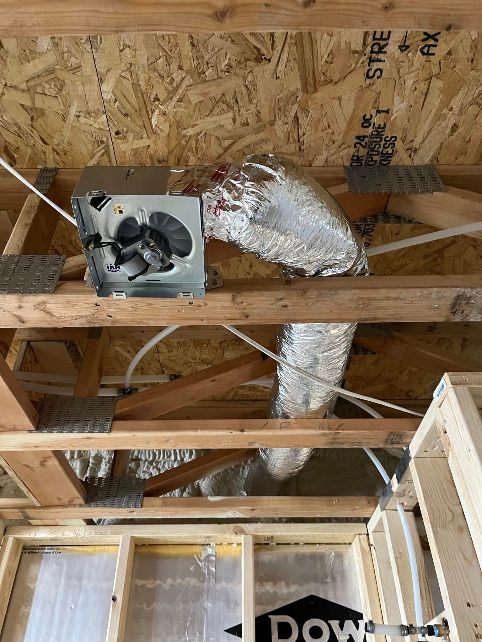 HVAC system in an attic with a fan, ductwork, and wooden framing.