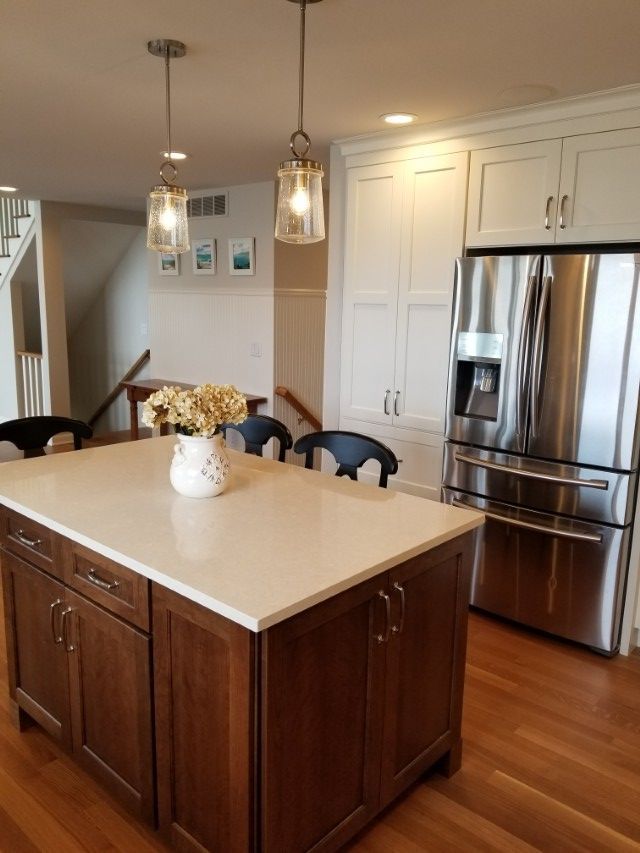 Modern kitchen with island, stainless steel fridge, pendant lights, and hardwood floors