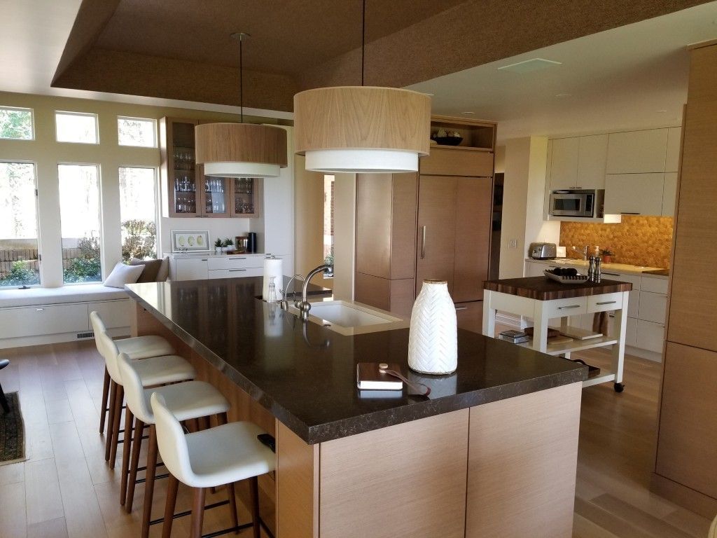 Modern kitchen with large island, bar stools, pendant lights, and wood cabinetry