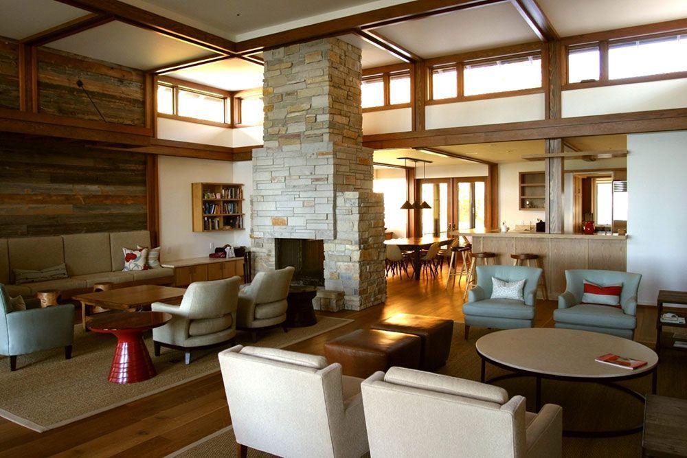 Spacious living room with fireplace, light blue and beige furniture, wooden beams, and natural light.