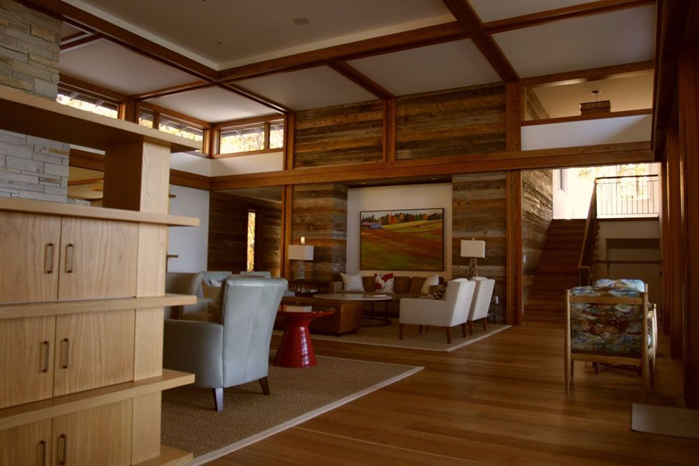 Interior view of a wood-paneled living room with furniture, artwork, and a staircase to the upper level.