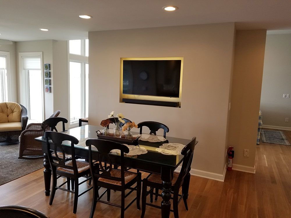 Dining area with black table, chairs, and TV mounted in a wall.
