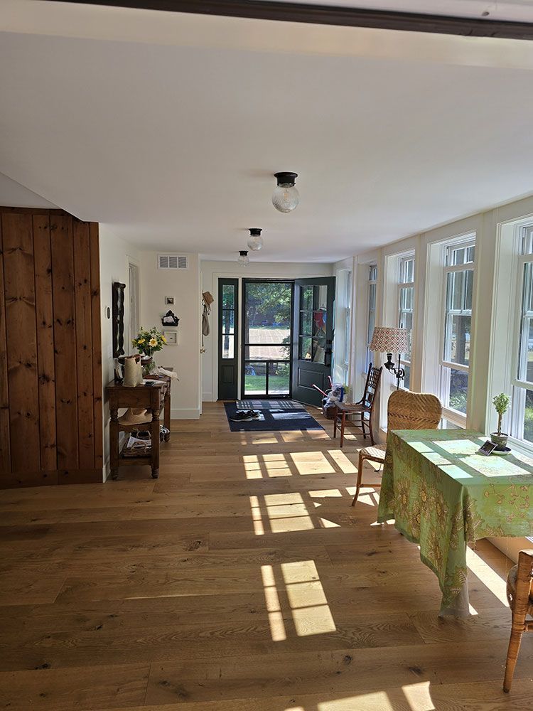 Sunlit interior with wood floors, windows, and dining table set for lunch.