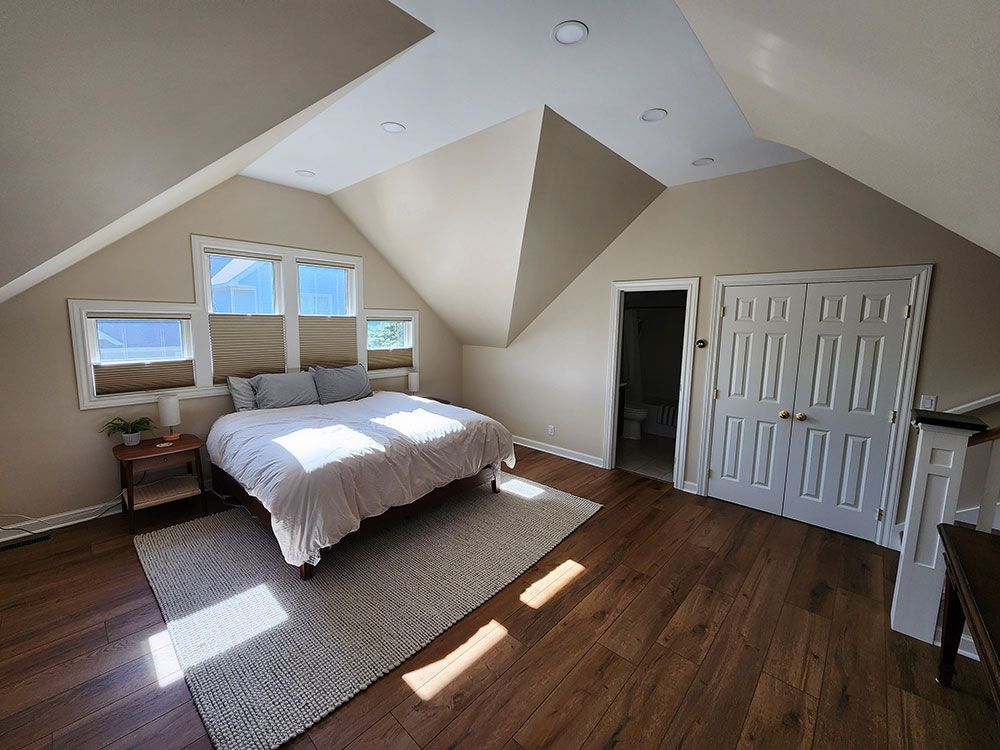 Bedroom with angled walls, bed, rug, and hardwood floors.