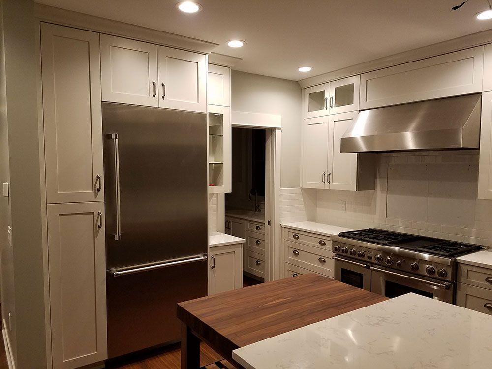 White kitchen with stainless steel appliances and dark wood island.