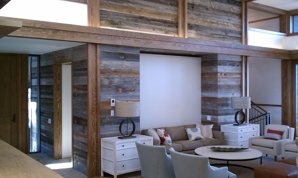 Living room with wooden beams, paneled walls, sofa, chairs, white storage, and round coffee table.