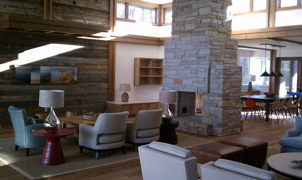 Living room with stone fireplace, wooden beams, and light-colored furniture.
