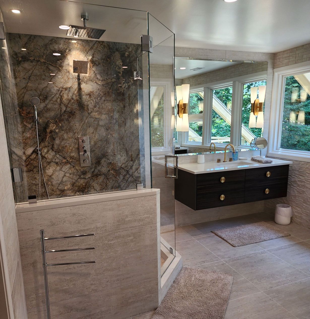 Bathroom with a marble shower, floating vanity, large mirror, and windows overlooking greenery.