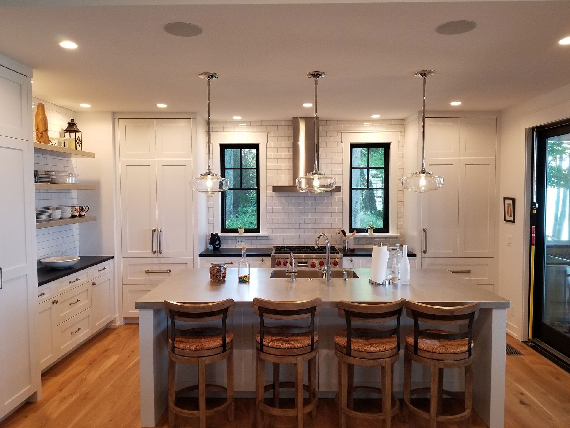 Modern kitchen with white cabinets, a large island with stools, and hanging lights.