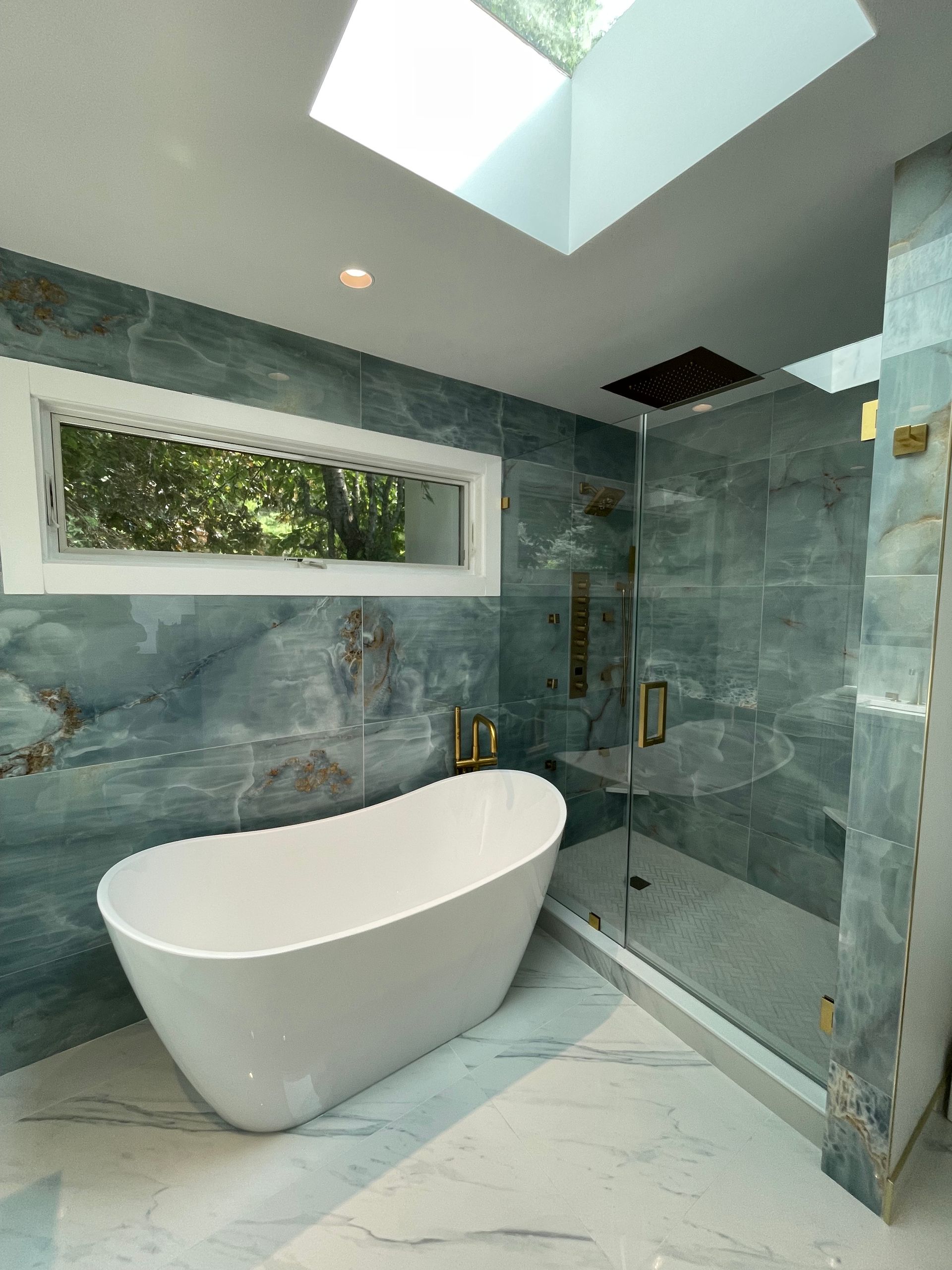 A bathroom with a tub and a shower with a skylight.