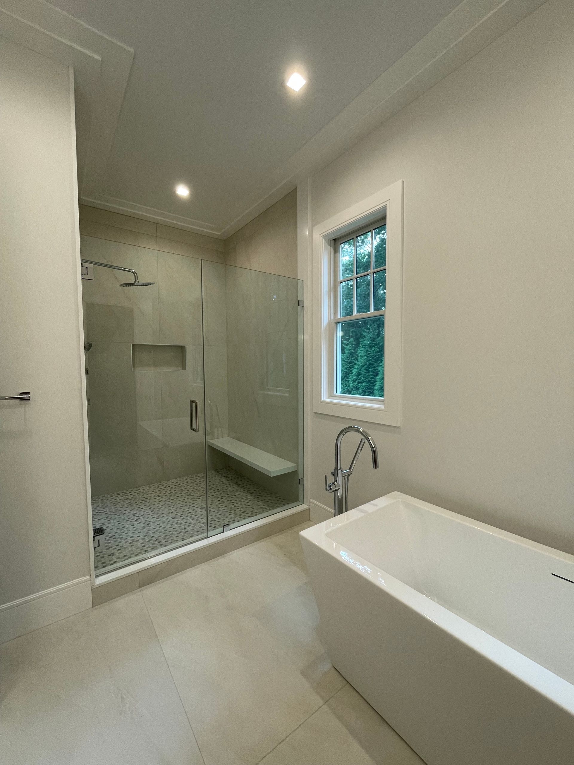 A bathroom with a tub , shower and window