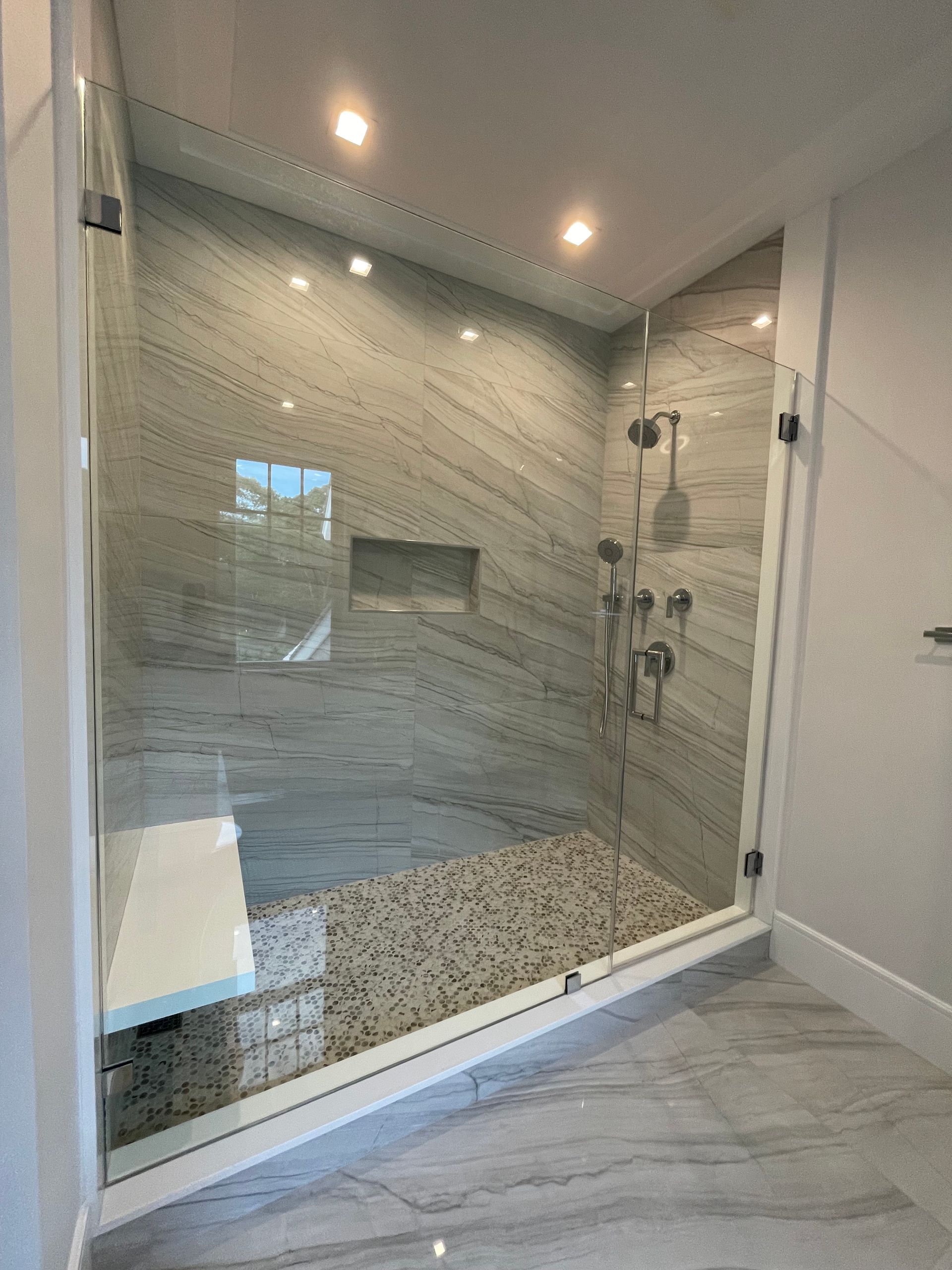 A bathroom with a walk in shower with a glass door.