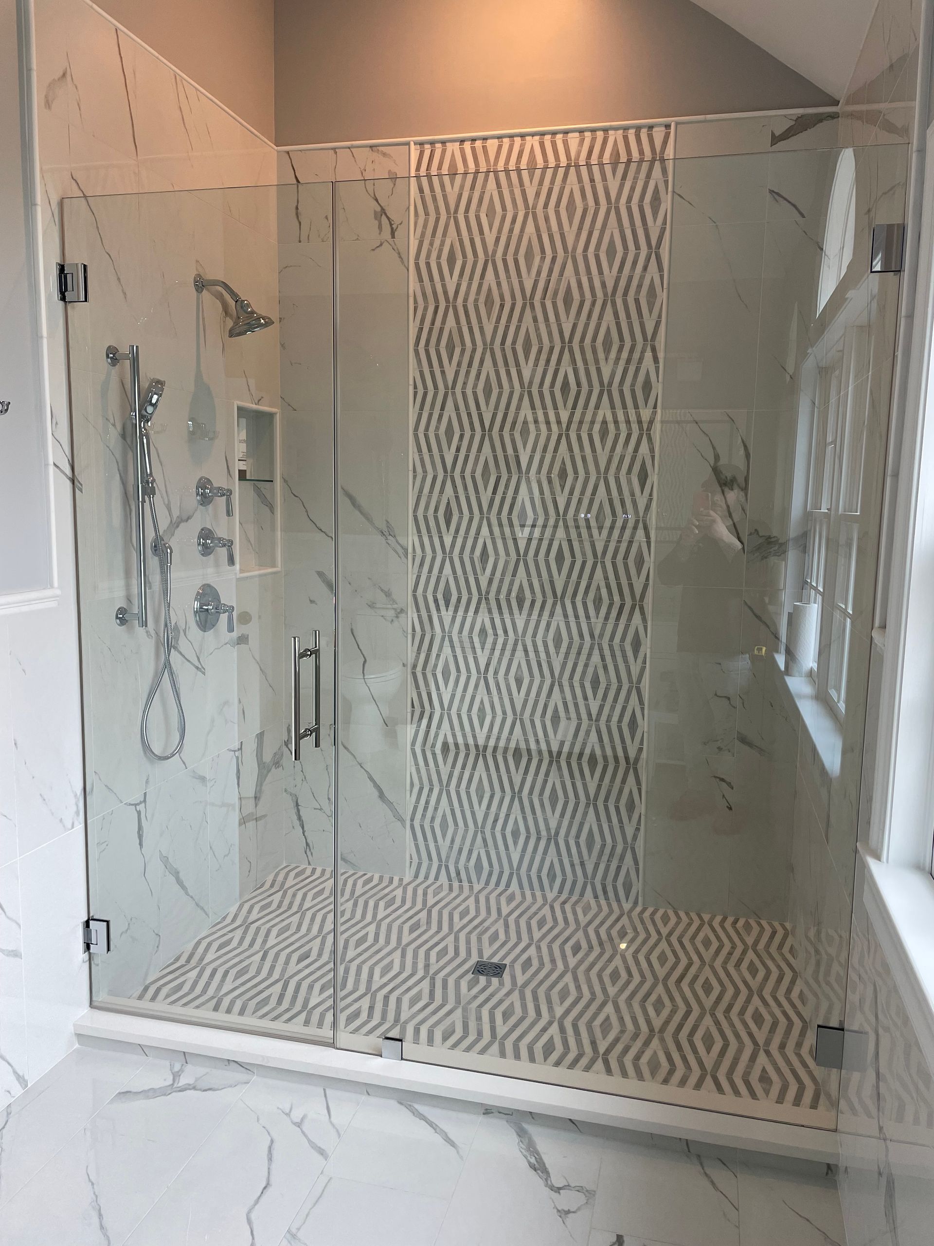 A bathroom with a walk in shower with a glass door.