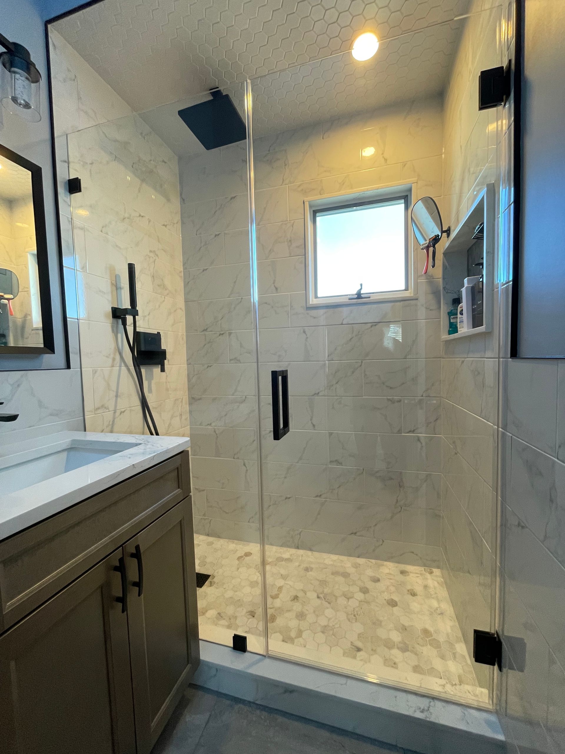 A bathroom with a walk in shower and a sink