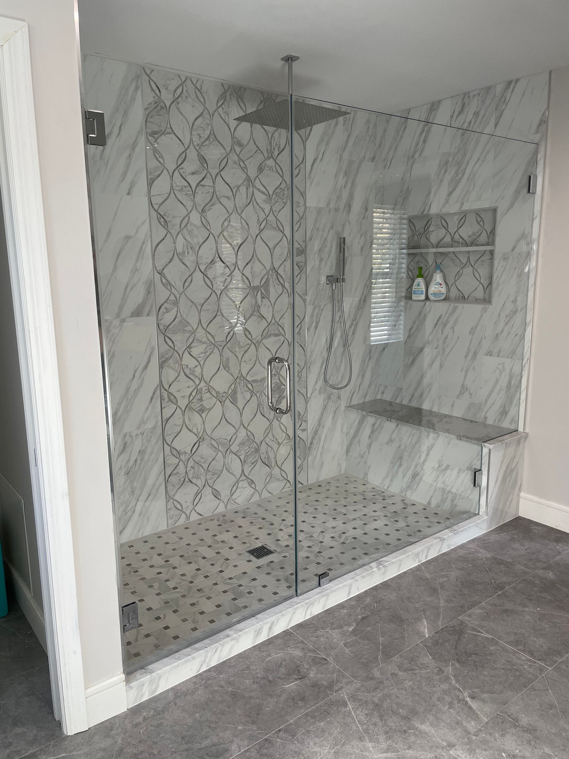 A bathroom with a walk in shower with a glass door.