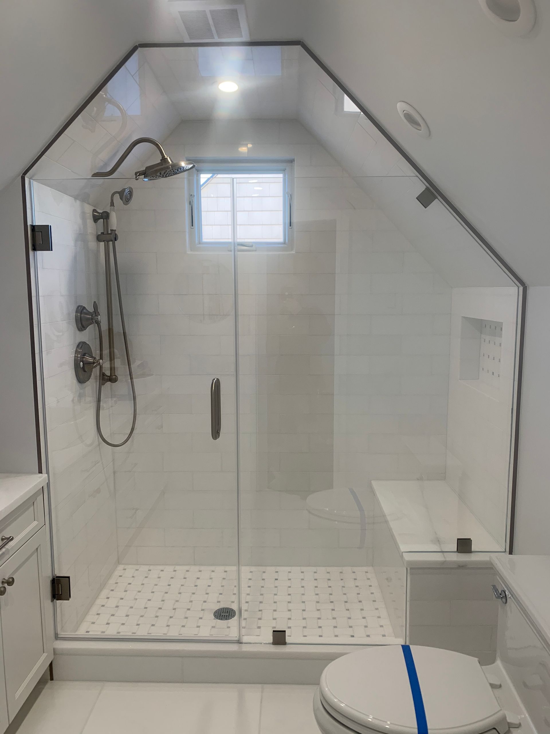 A bathroom with a glass shower door and a toilet.