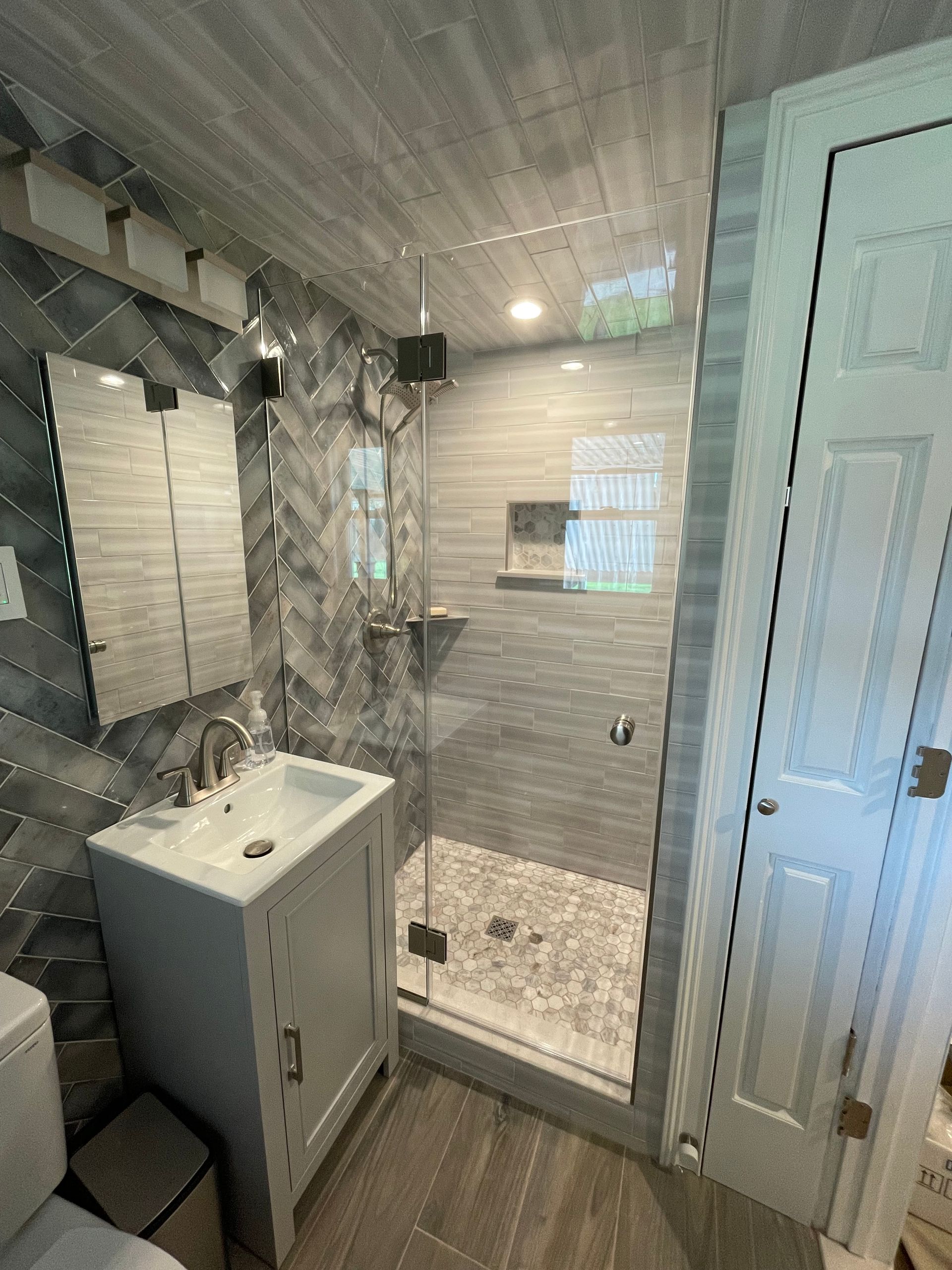 A bathroom with a sink , toilet , mirror and walk in shower.