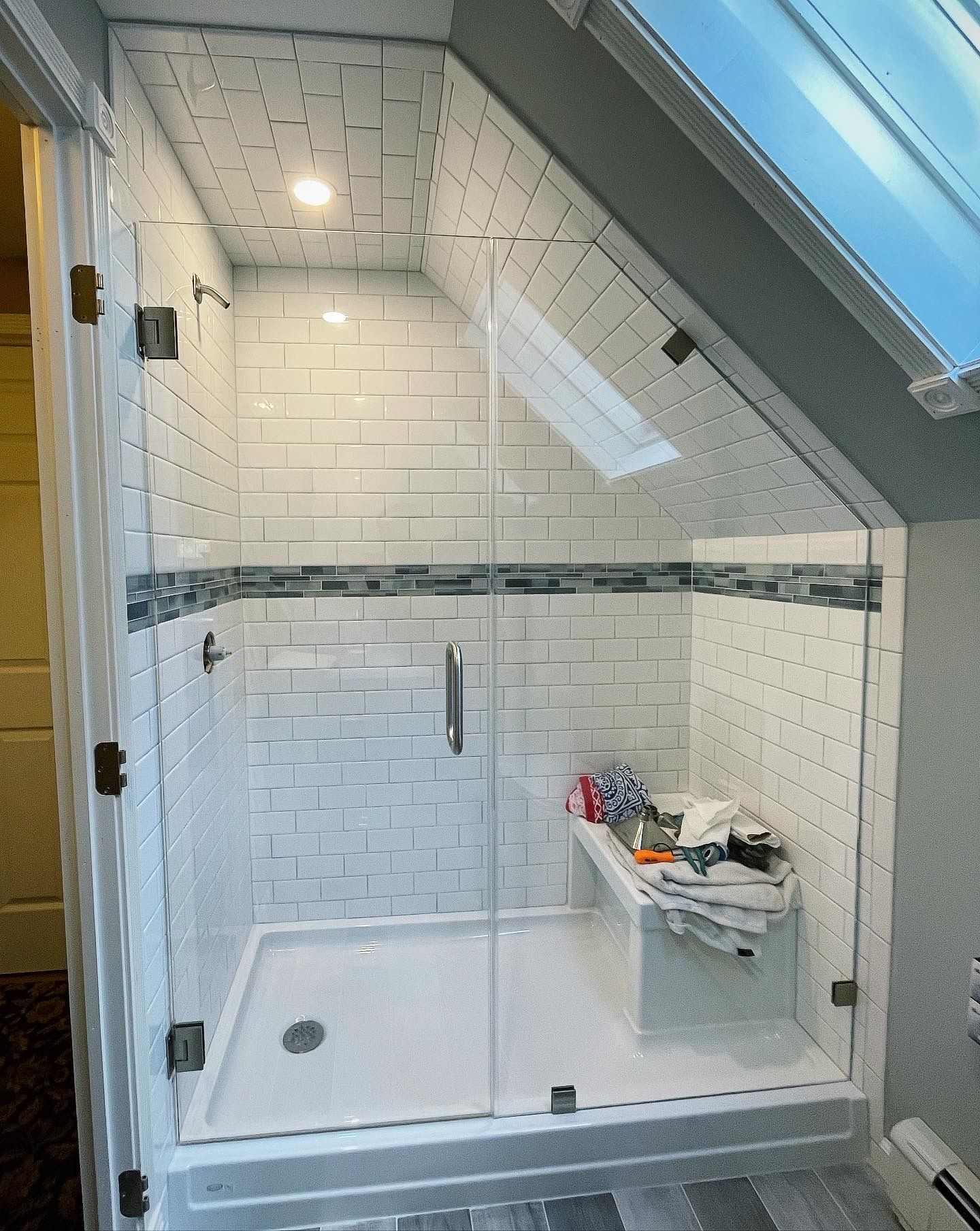 A bathroom with a walk in shower and a skylight