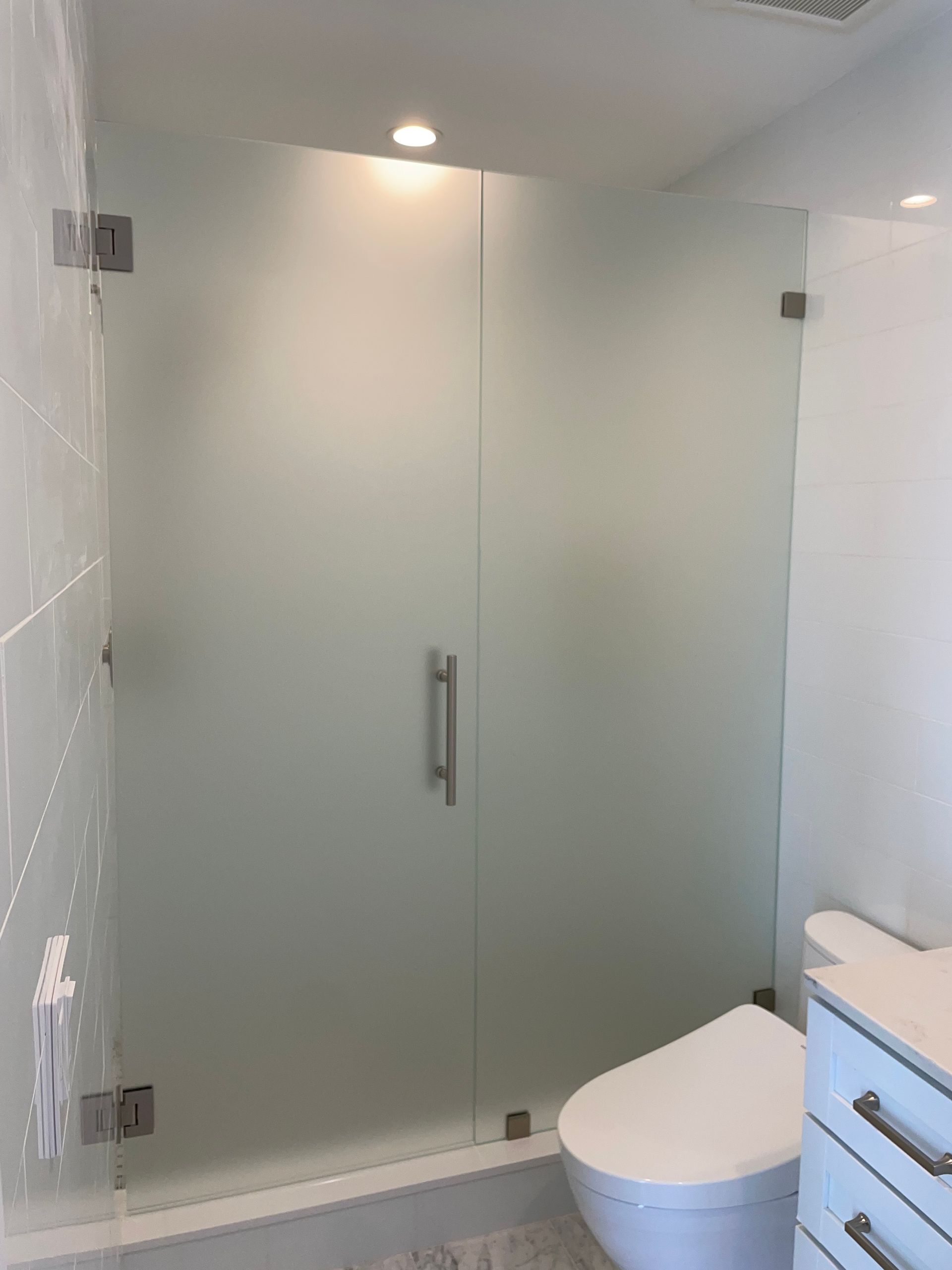 A bathroom with a toilet and a glass shower door.
