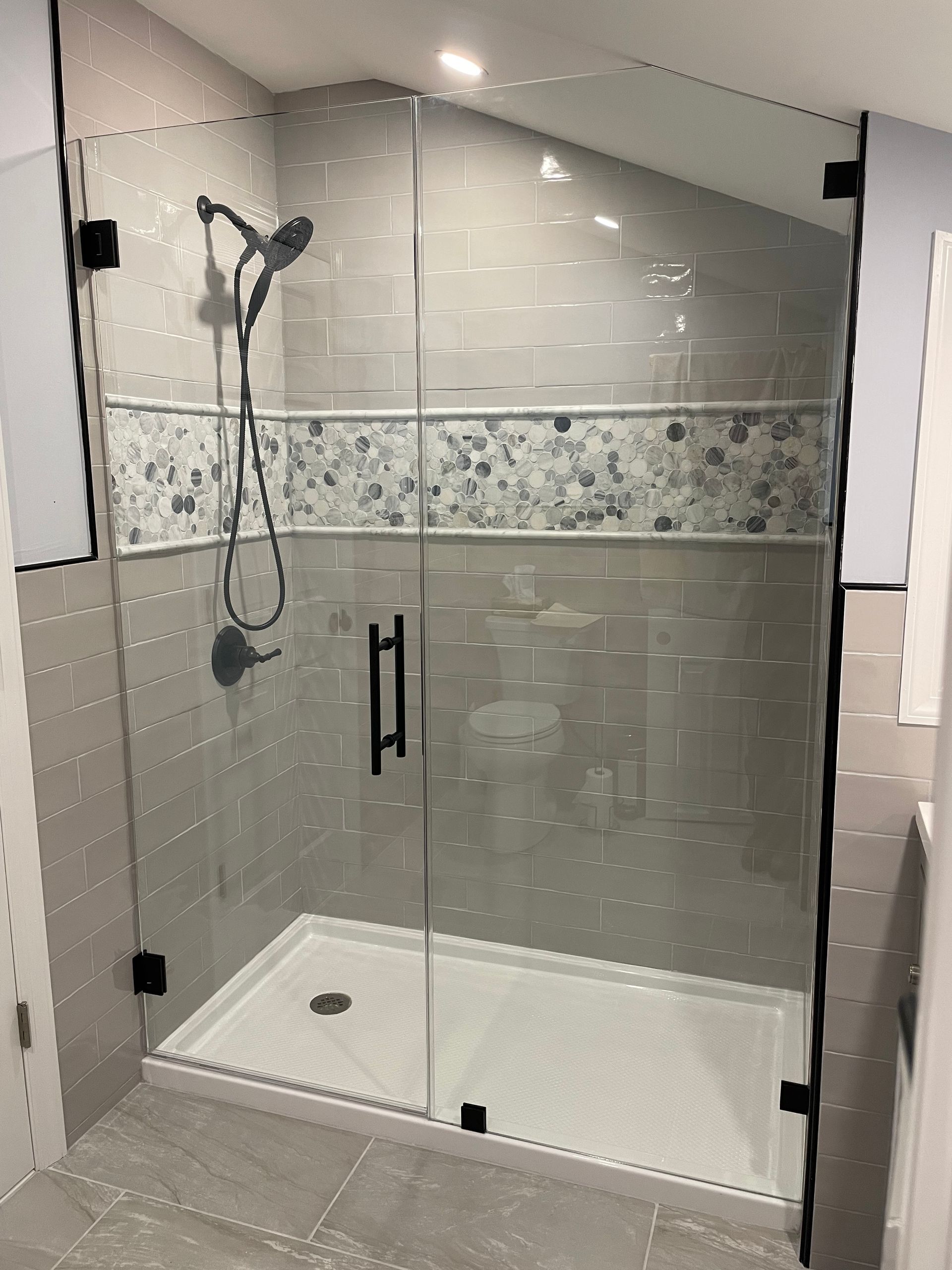 A bathroom with a walk in shower and a shower head.