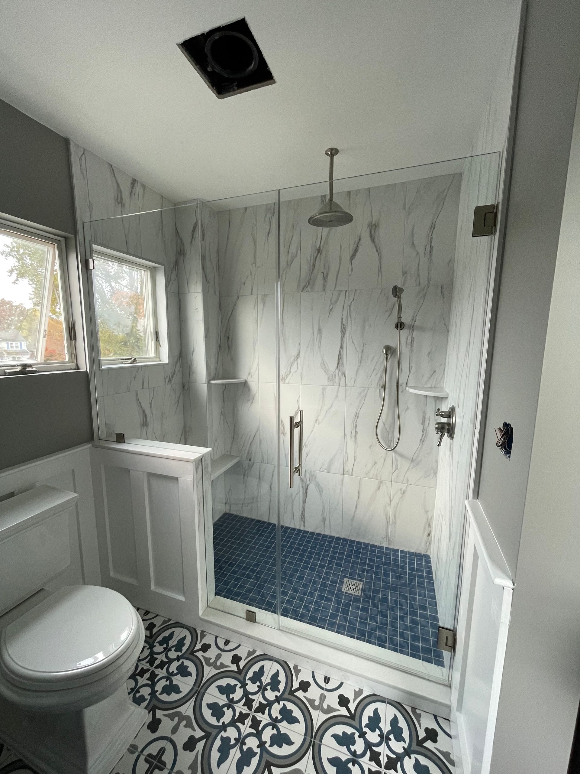 A bathroom with a toilet , shower , and window.