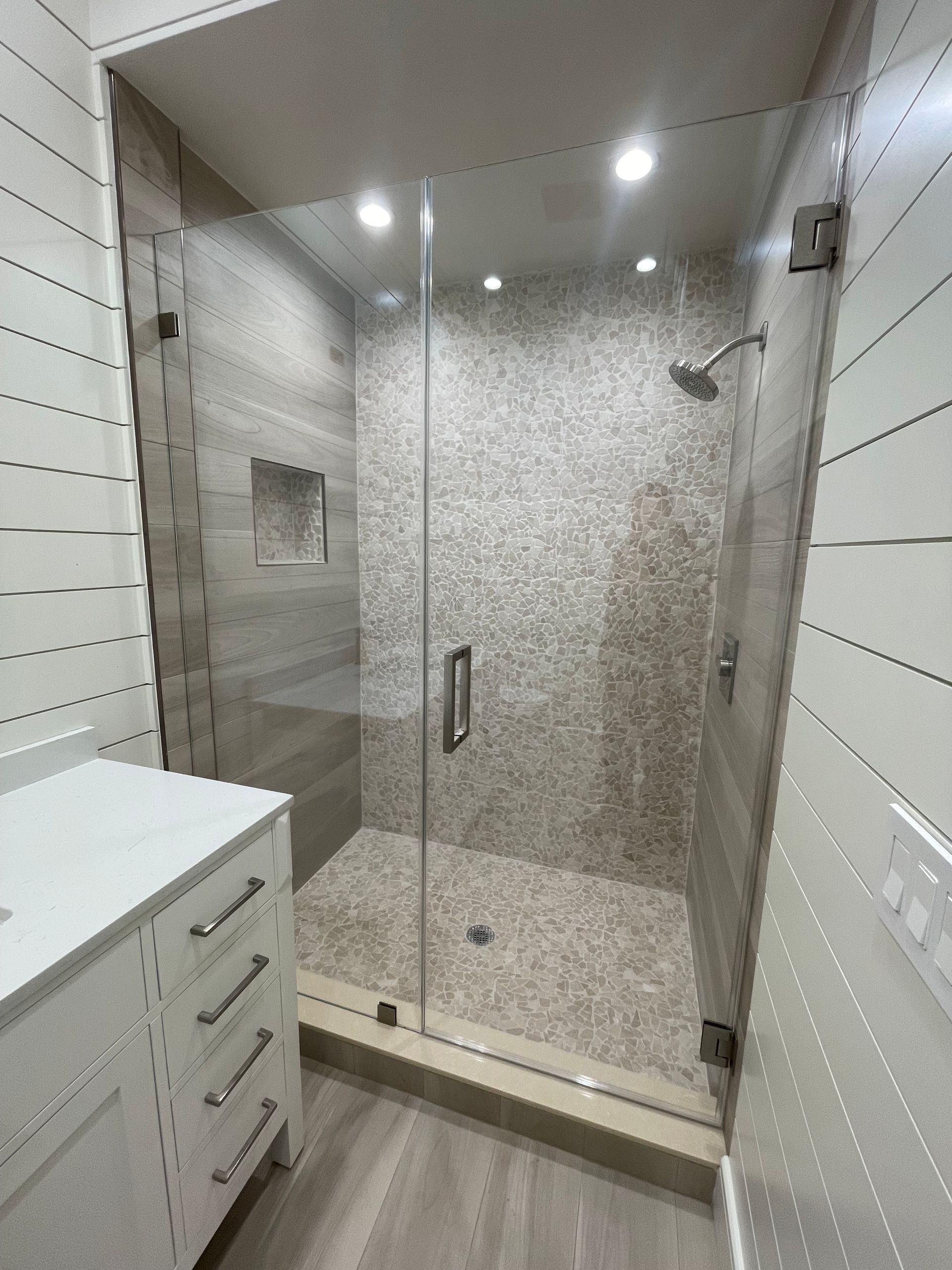 A bathroom with a walk in shower and a sink.