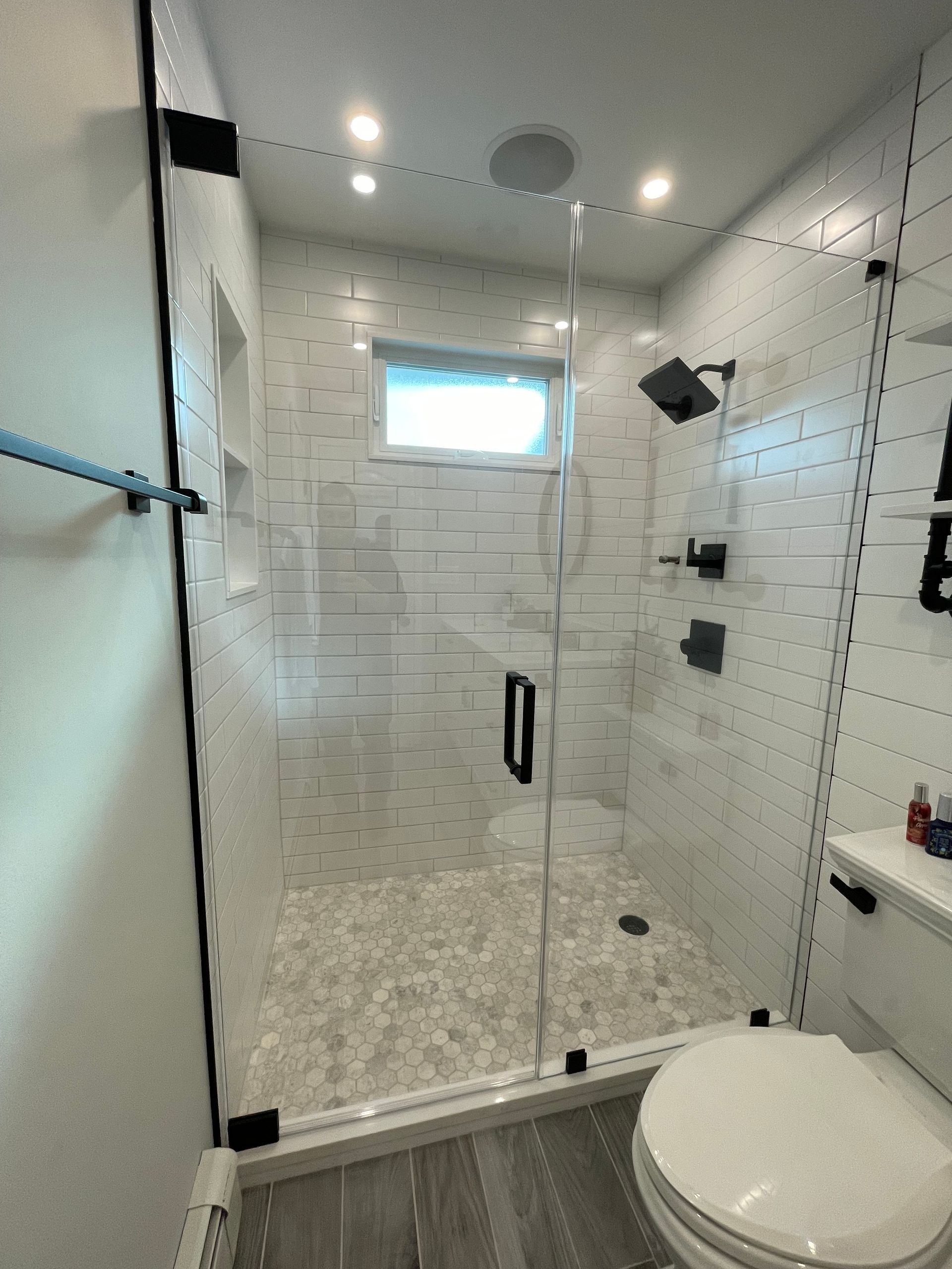 A bathroom with a toilet , shower , and window.