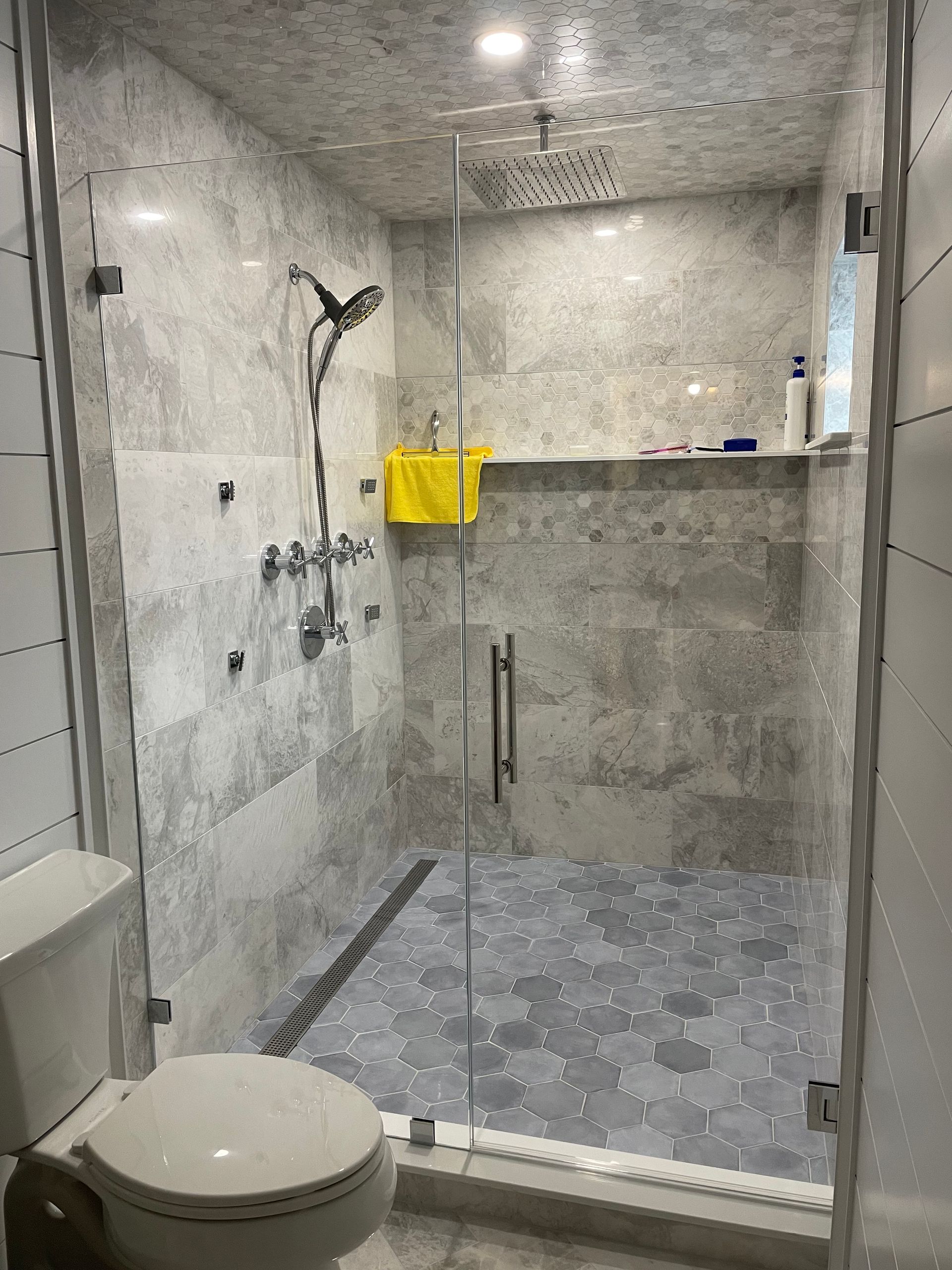 A bathroom with a toilet , shower , and glass door.