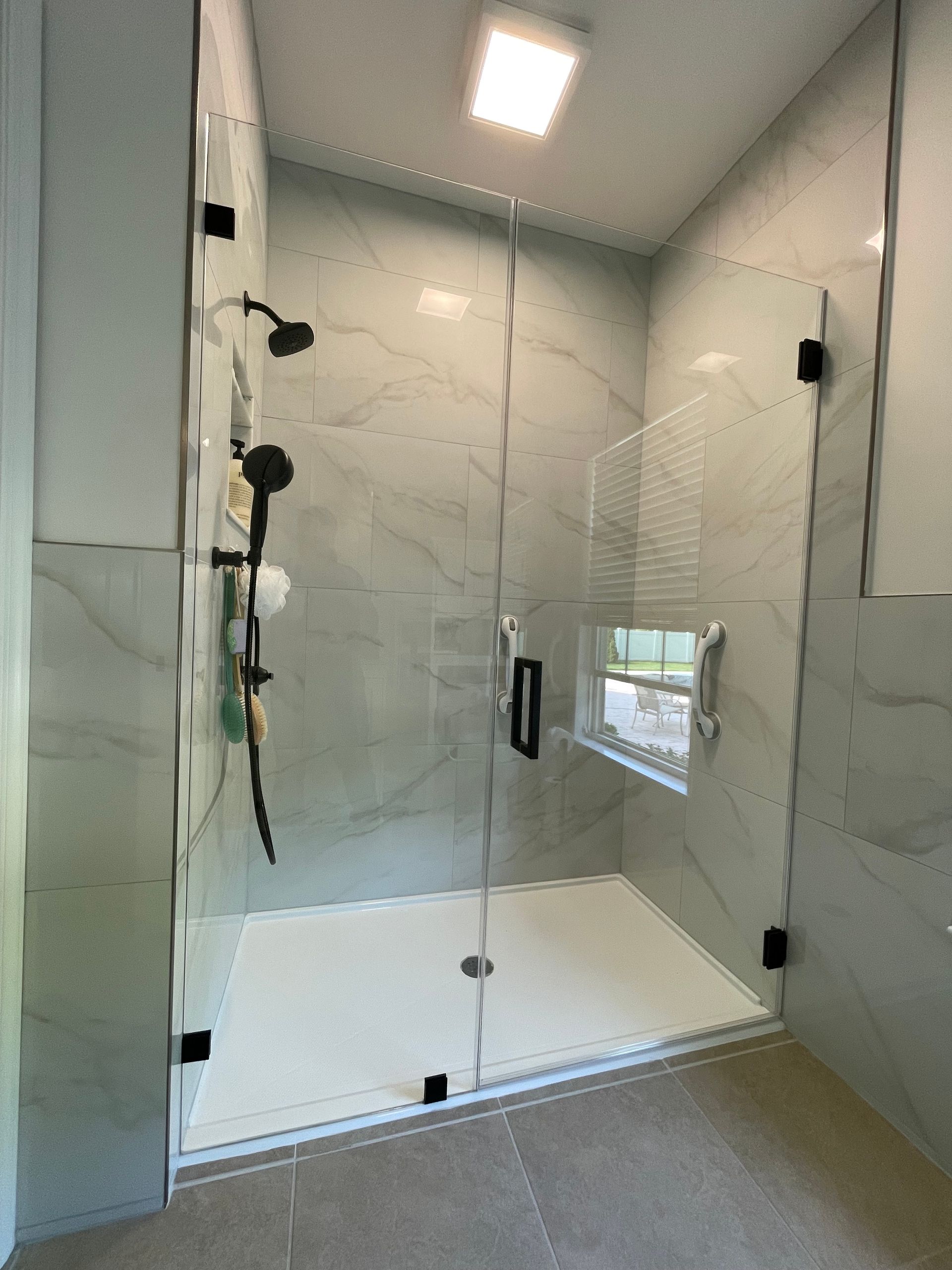 A bathroom with a walk in shower with a glass door.
