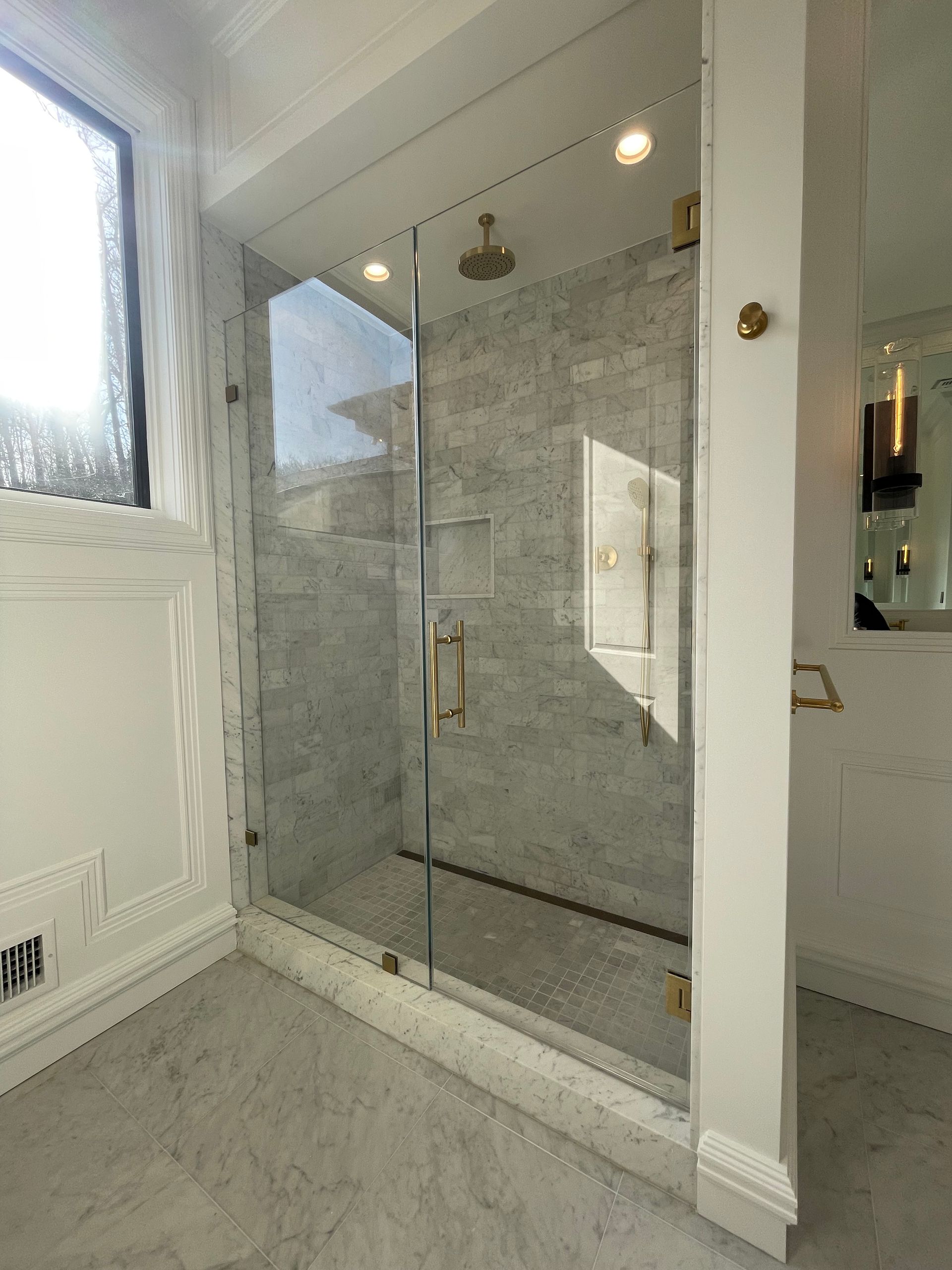 A bathroom with a walk in shower and a window.