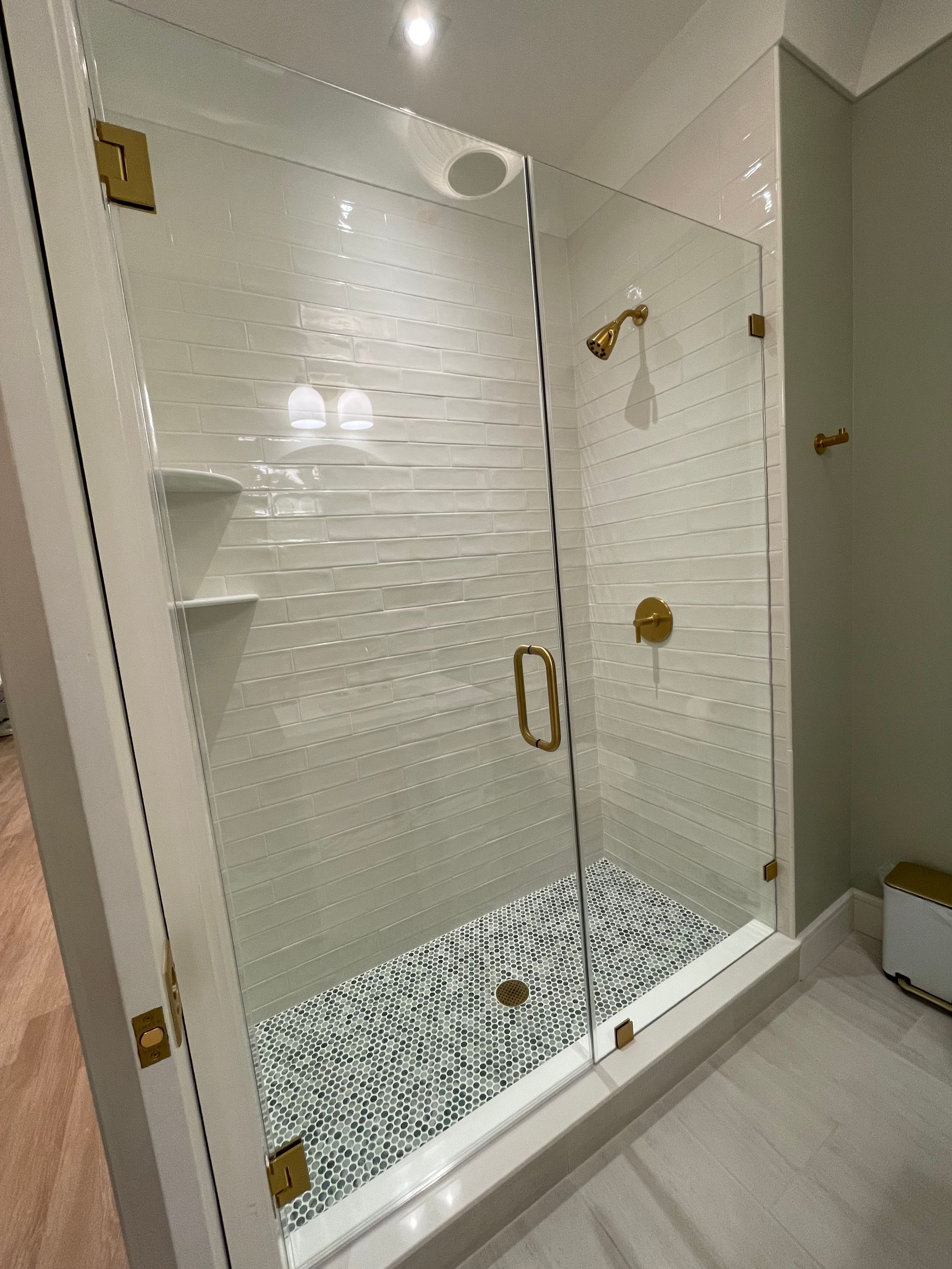 A bathroom with a walk in shower with a glass door.