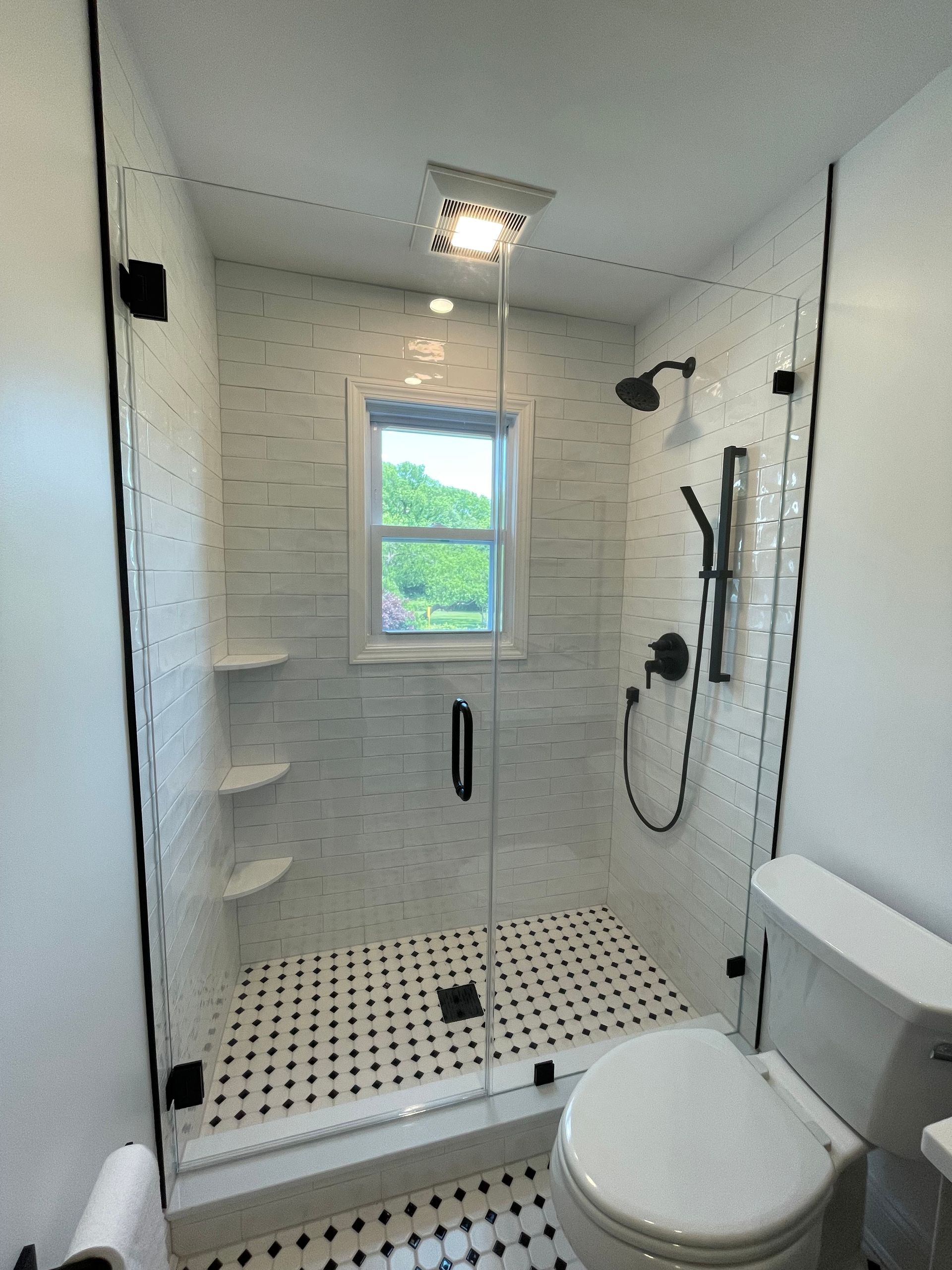 A bathroom with a toilet , shower and window