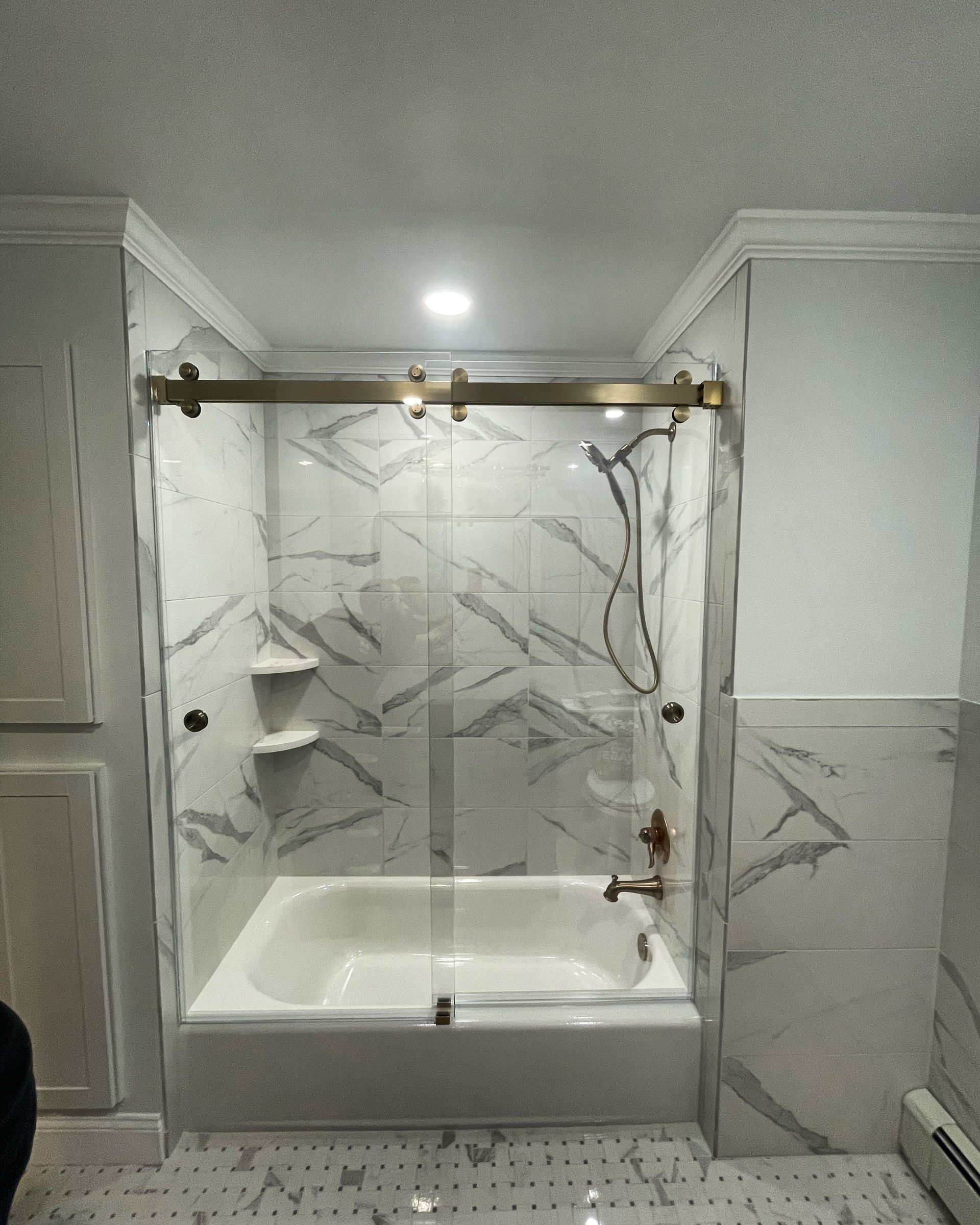 A bathroom with a bathtub and a sliding glass shower door