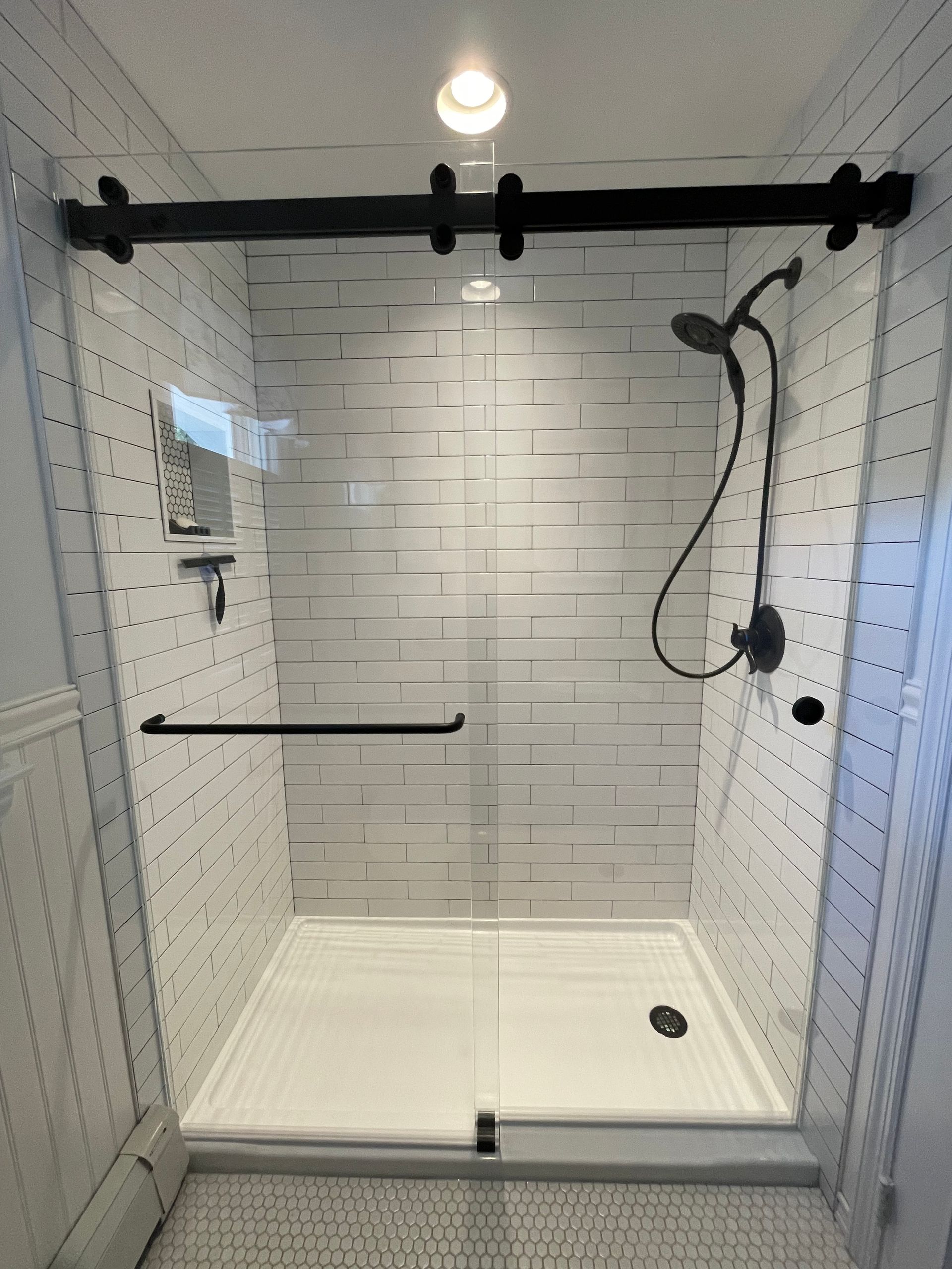 A shower with a sliding glass door and a shower head