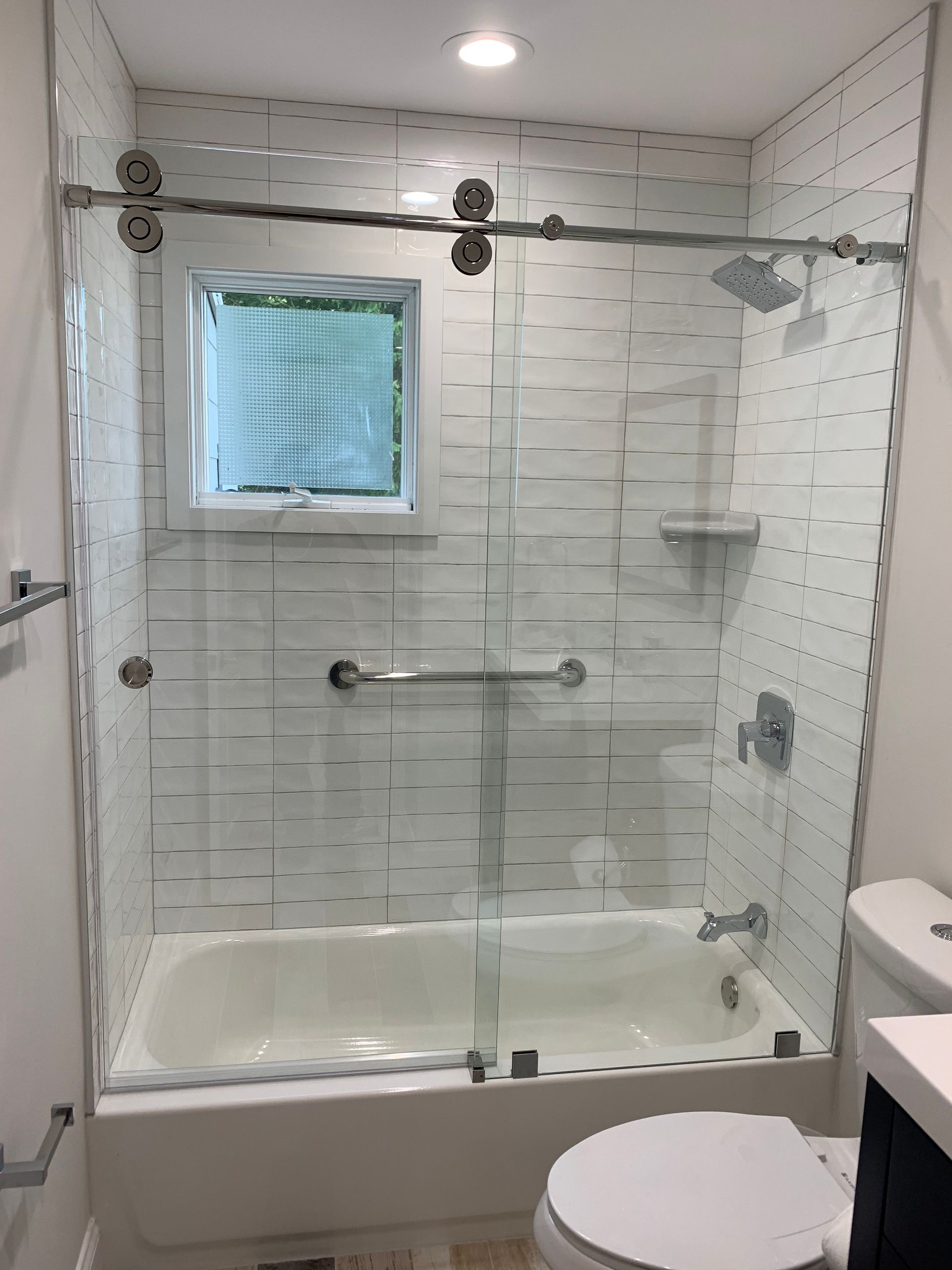 A bathroom with a tub , toilet , shower and window.