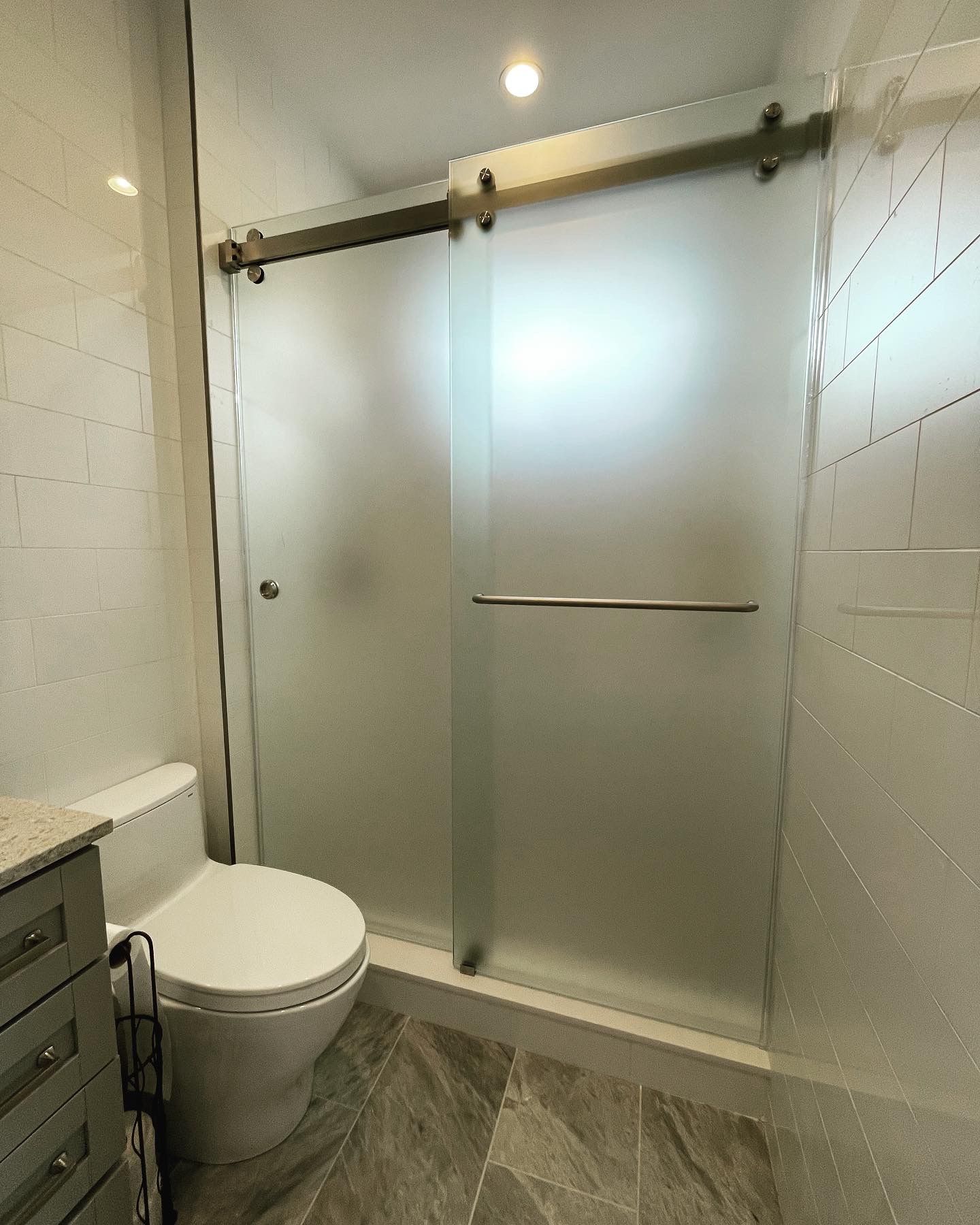 A bathroom with a toilet and a sliding glass shower door.