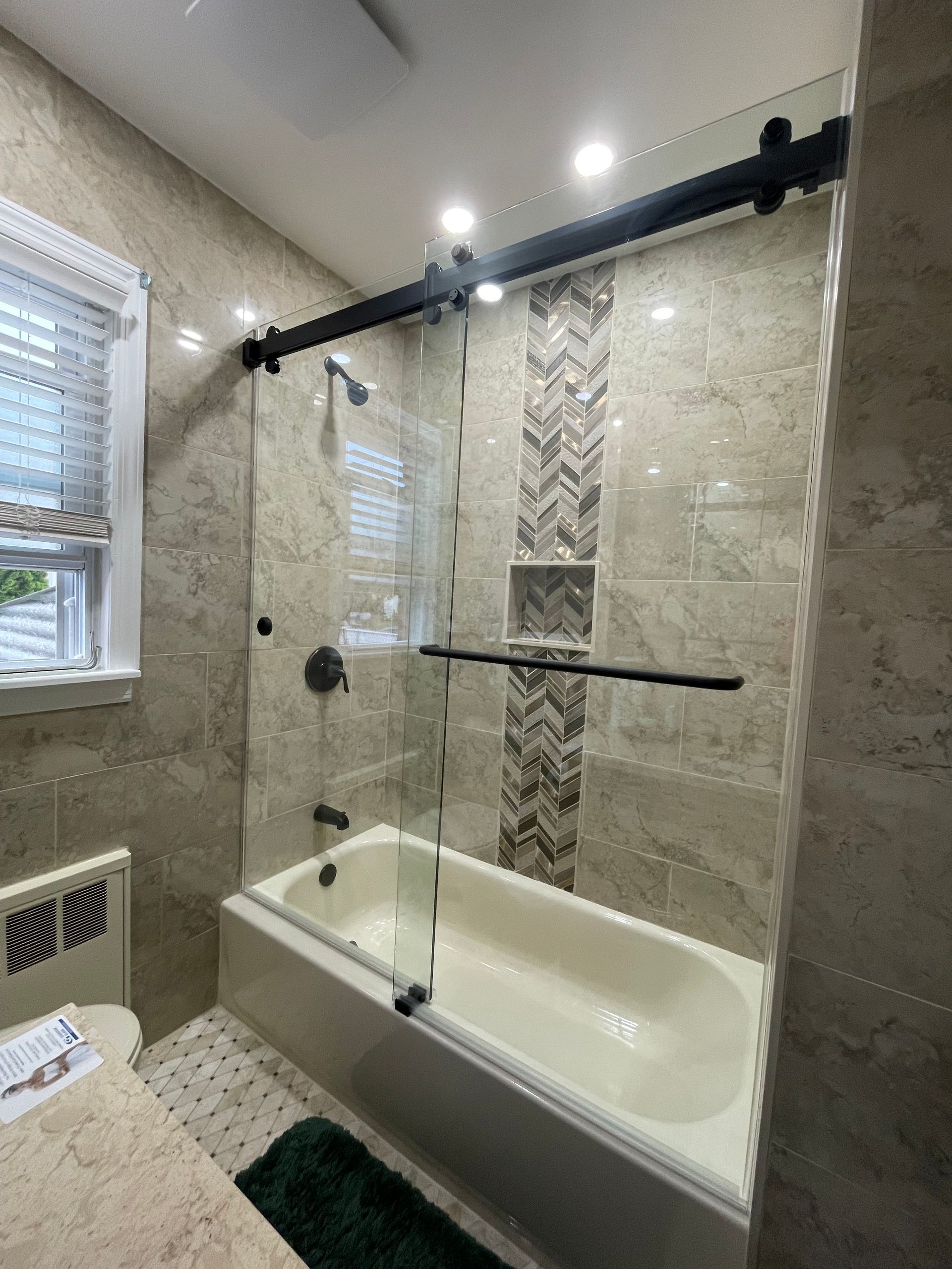 There is a bathtub in the bathroom with a sliding glass shower door.